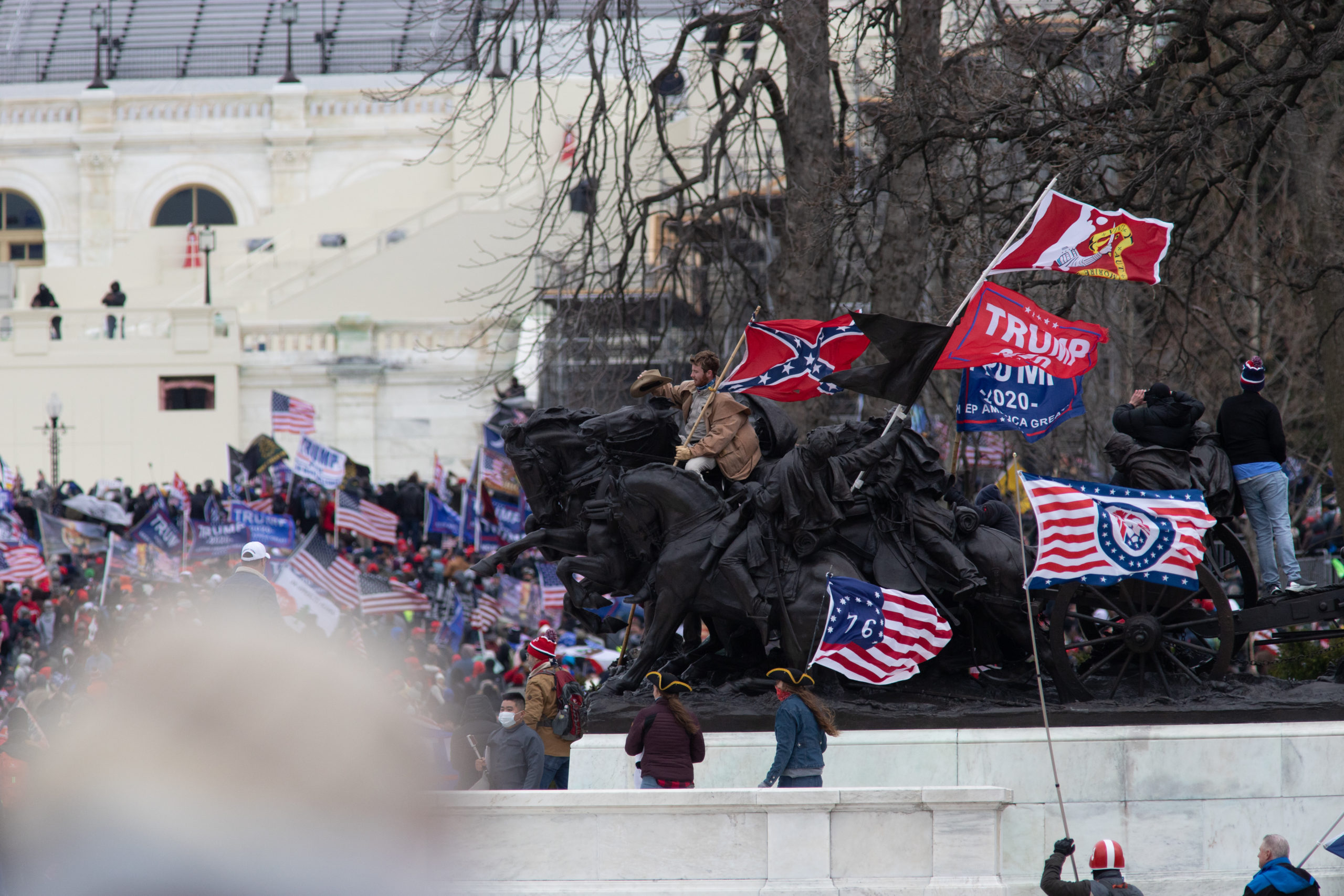 A man mounted a horse statue in front of the U.S. Capitol while holding a Confederate flag in Washington, D.C. on Jan. 6, 2021. (Kaylee Greenlee – Daily Caller News Foundation)