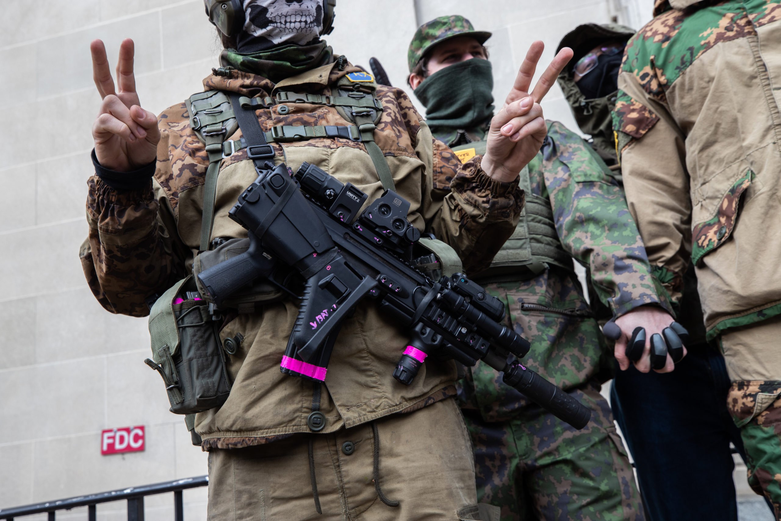 An armed demonstrator made a hand gesture while wearing a patch associated with a 4 Chan board catalog in Richmond, Virginia on January 18, 2021. (Kaylee Greenlee - Daily Caller News Foundation)