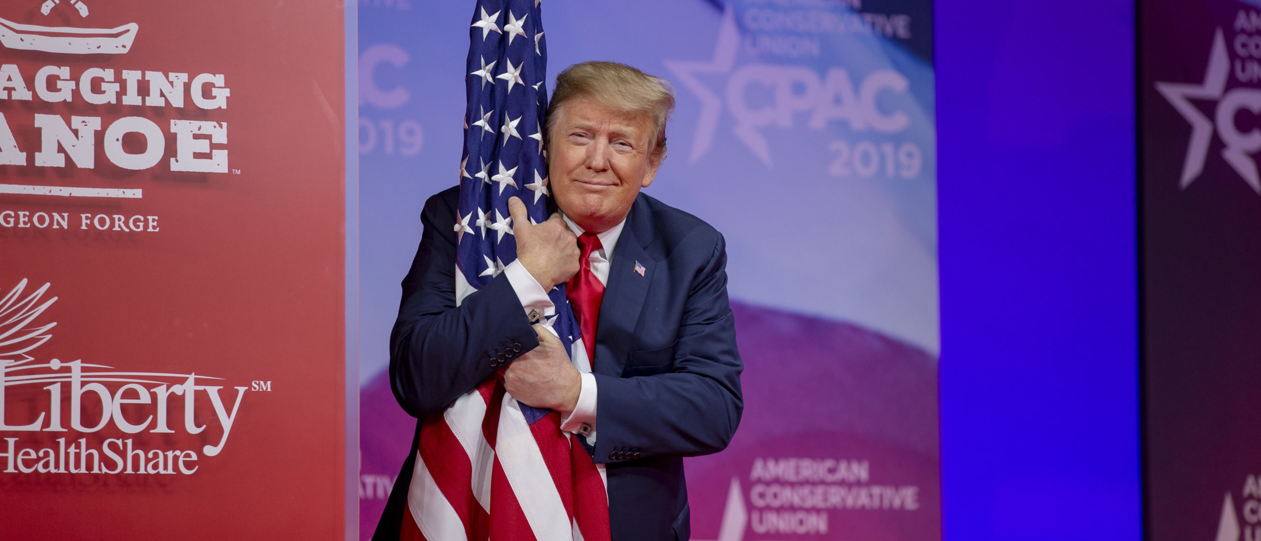 U.S. President Donald Trump hugs the U.S. flag during CPAC 2019 on March 02, 2019 in National Harbor, Maryland. (Photo by Tasos Katopodis/Getty Images)