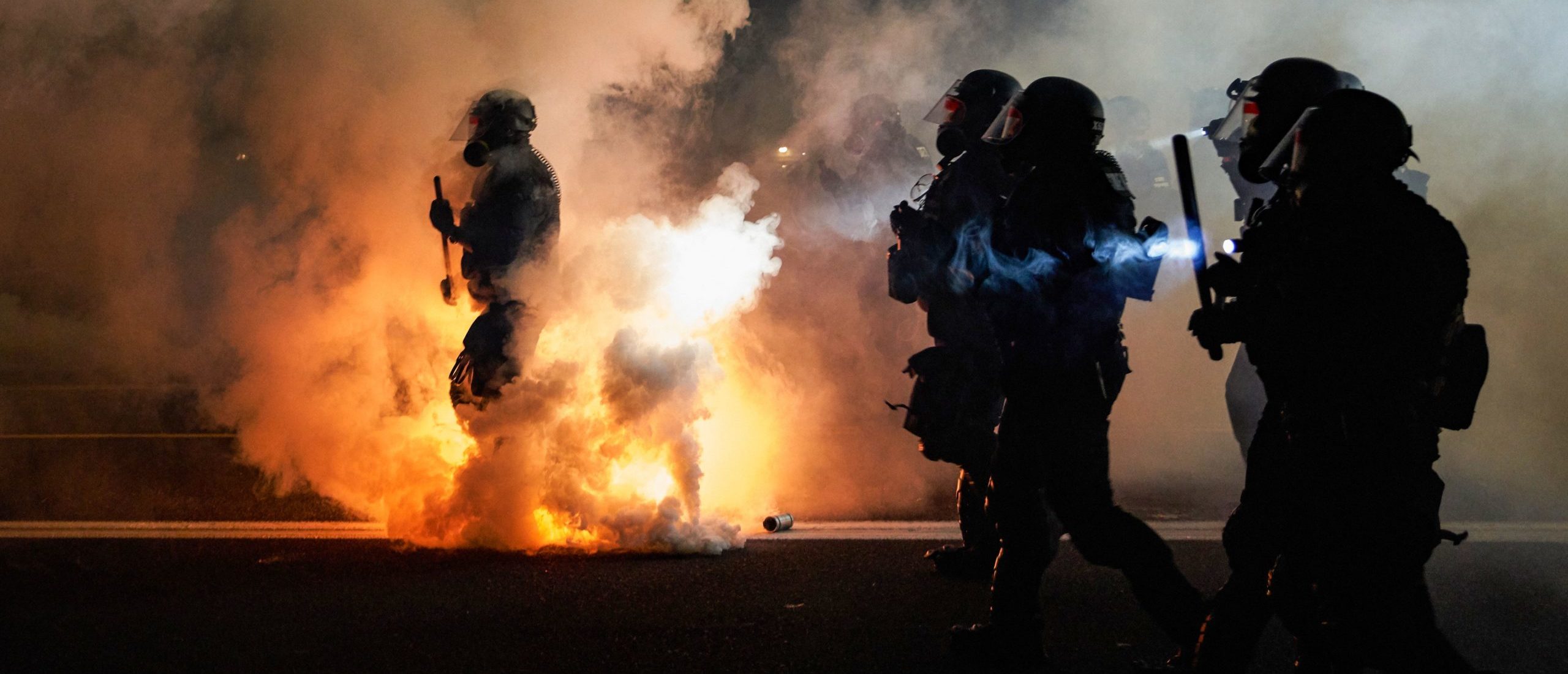 TOPSHOT - Oregon Police wearing anti-riot gear march towards protesters through tear gas smoke during the 100th day and night of protests against racism and police brutality in Portland, Oregon, on September 5, 2020. - Police arrested dozens of people and used tear gas against hundreds of demonstrators in Portland late on September 5 as the western US city marked 100 days since Black Lives Matter protests erupted against racism and police brutality. Protests in major US cities erupted after the death of African American George Floyd in May 2020 at the hands of a white police officer in Minneapolis. (Photo by Allison Dinner / AFP) (Photo by ALLISON DINNER/AFP via Getty Images)