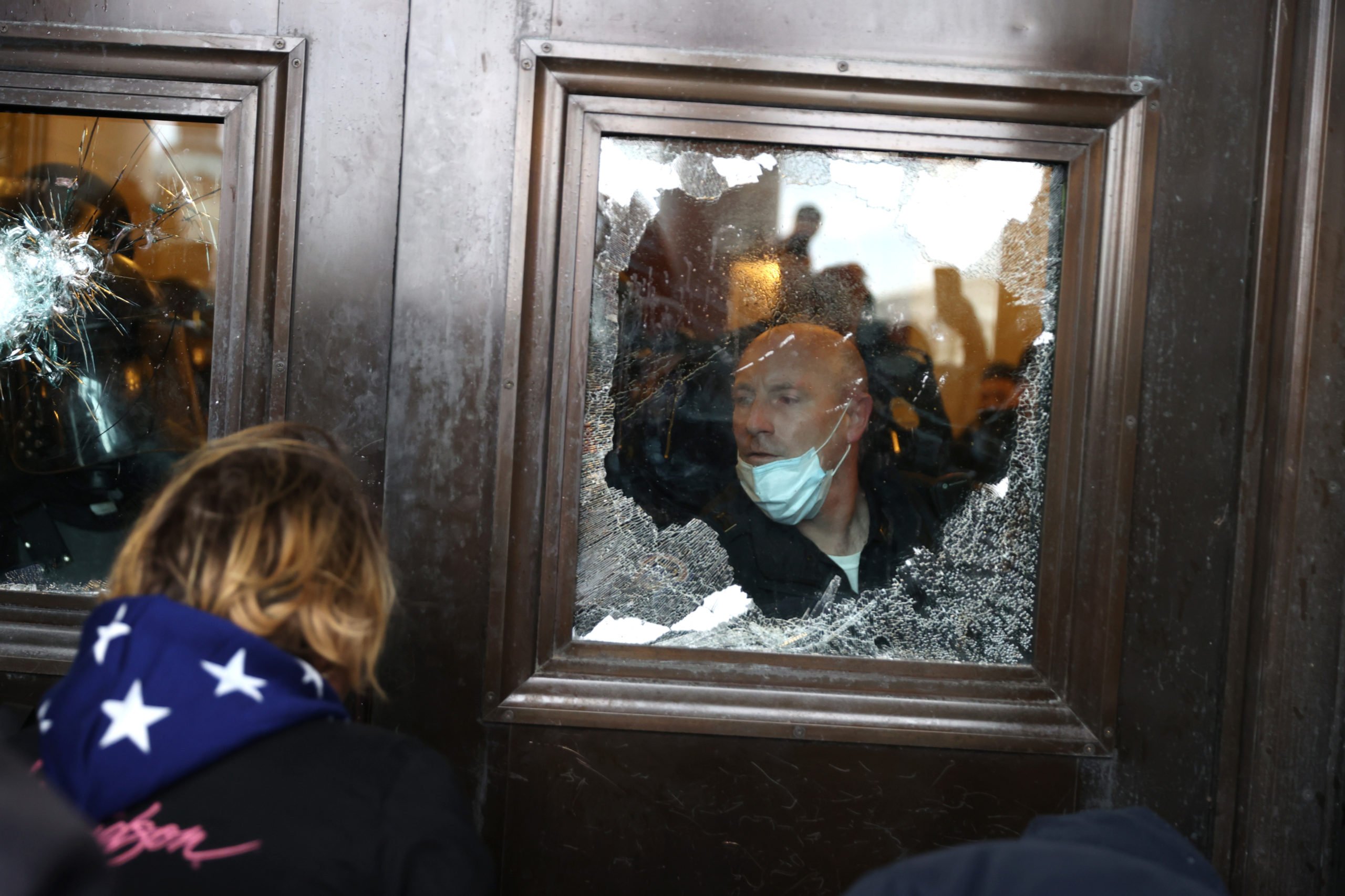 A Capitol police officer looks out of a broken window as protesters gather on the U.S. Capitol Building on January 06, 2021 in Washington, DC. (Tasos Katopodis/Getty Images)