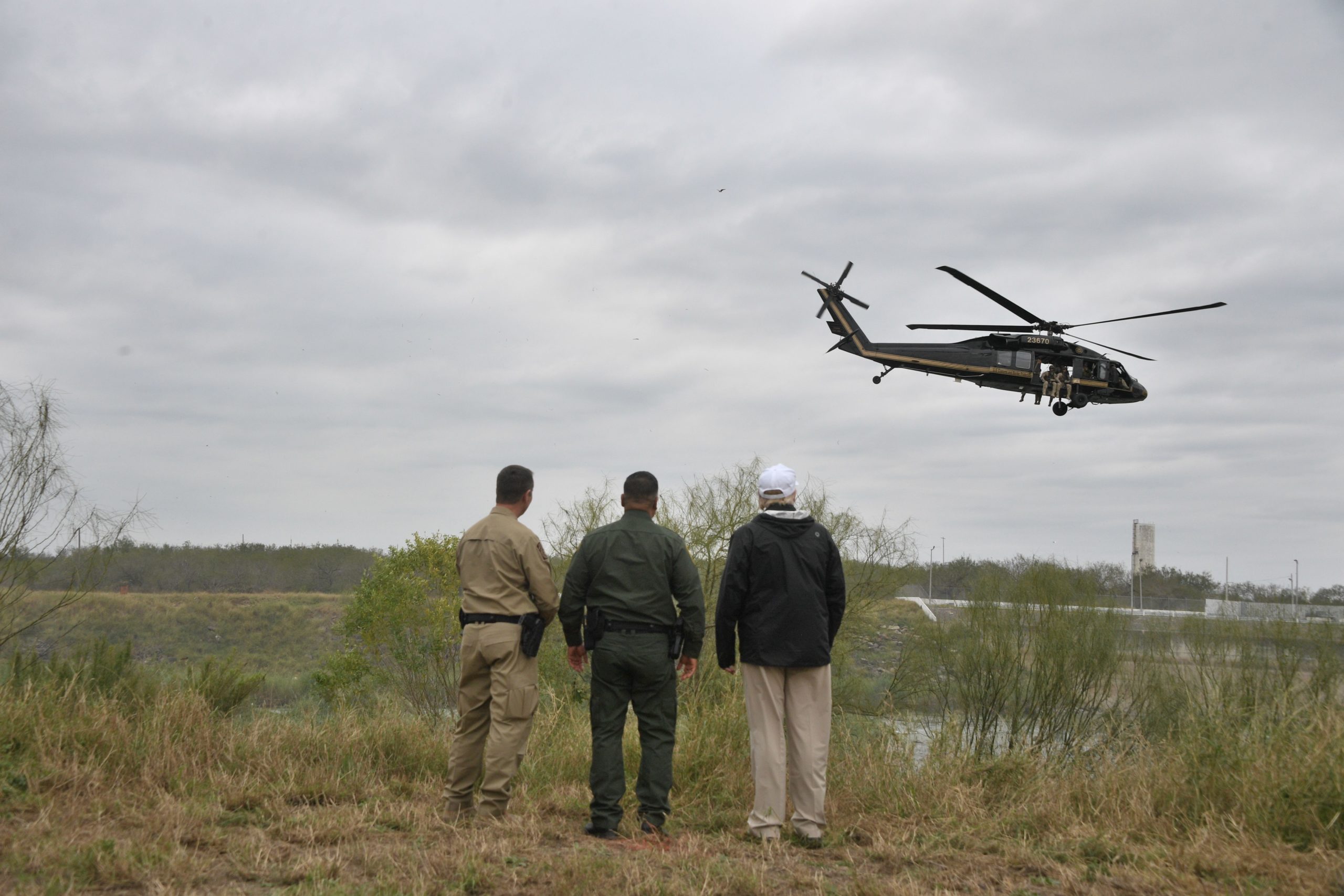 US President Donald Trump stands with Border Patrol agents at the Rio Grande as a US Customs and Border Protection (CBP) helicopter flew overhead, after his visit to US Border Patrol McAllen Station in McAllen, Texas, on January 10, 2019. - Trump traveled to the US-Mexico border as part of his all-out offensive to build a wall, a day after he stormed out of negotiations when Democratic opponents refused to agree to fund the project in exchange for an end to a painful government shutdown. (Photo by Jim WATSON / AFP) (Photo credit should read JIM WATSON/AFP via Getty Images)