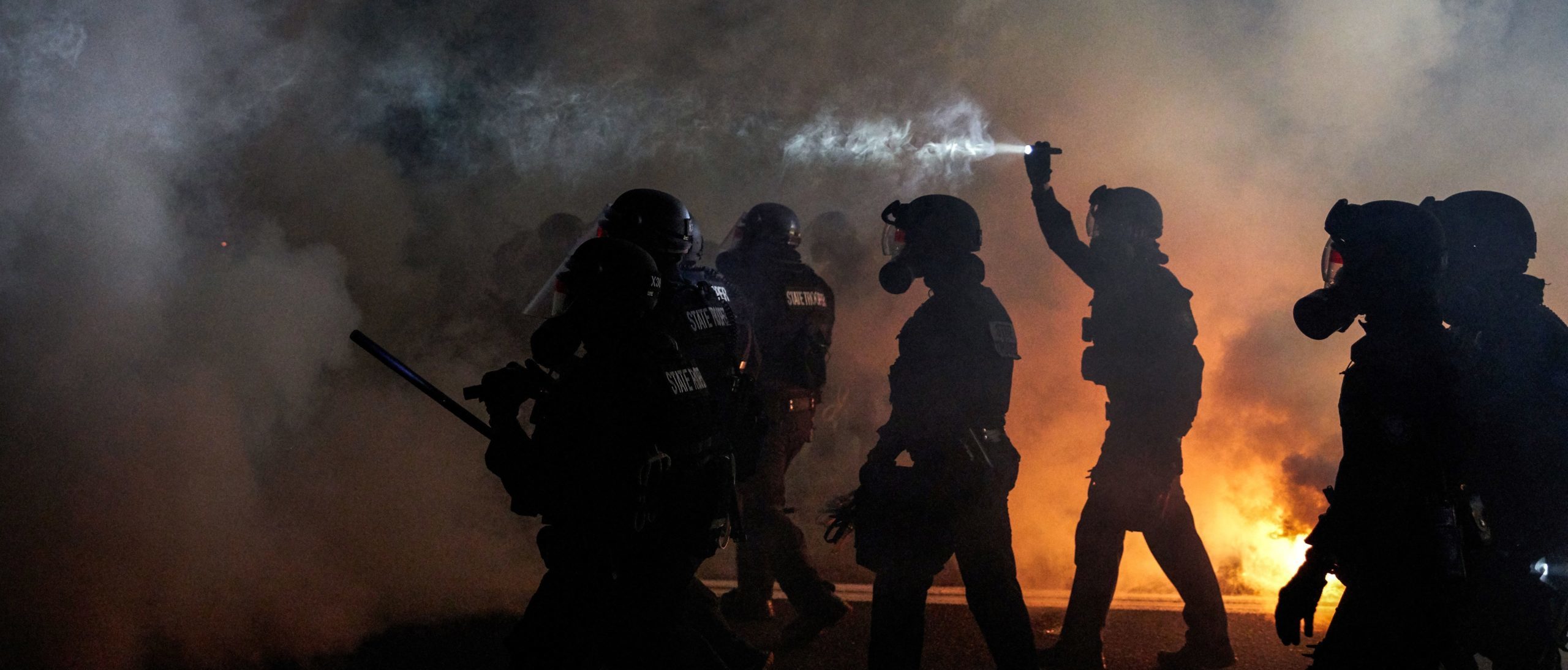 Oregon Police wearing anti-riot gear march towards protesters through tear gas smoke during the 100th day and night of protests against racism and police brutality in Portland, Oregon, on September 5, 2020. (Photo by ALLISON DINNER/AFP via Getty Images)