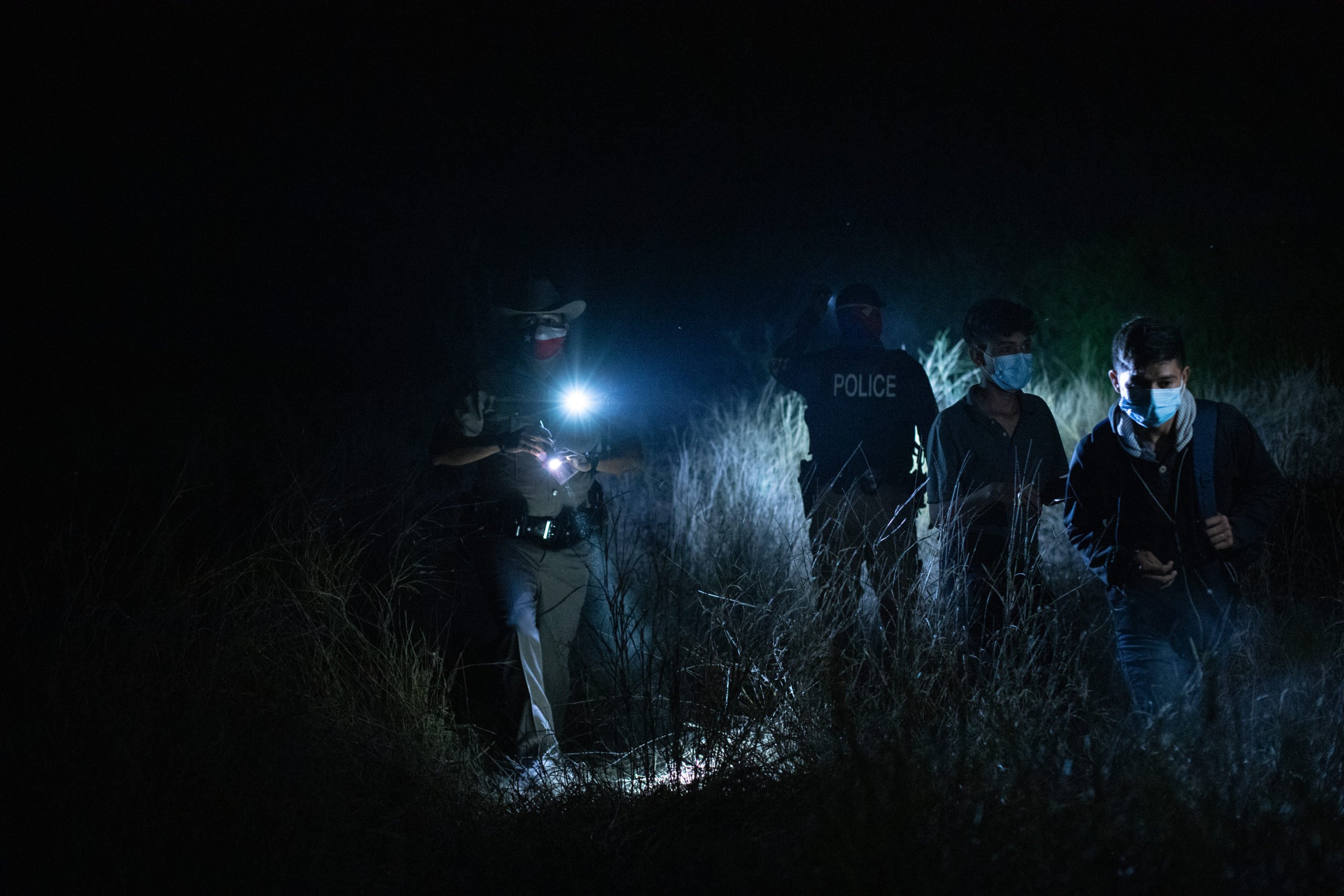 Texas state and local law enforcement officials helped a group migrants cross over a barbed wire fence and line of train tracks after they illegally entered the U.S. near La Joya, Texas on March 25, 2021. (Kaylee Greenlee - Daily Caller News Foundation)
