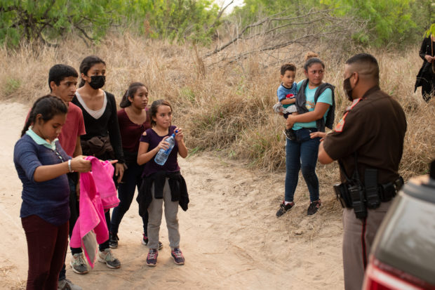An official with the Hidalgo County Constable's office gathers biometric data from illegal immigrants shortly after they were smuggled into the U.S. in Rincon Village near McAllen, Texas, on March 24, 2021. (Kaylee Greenlee. - Daily Caller News Foundation)