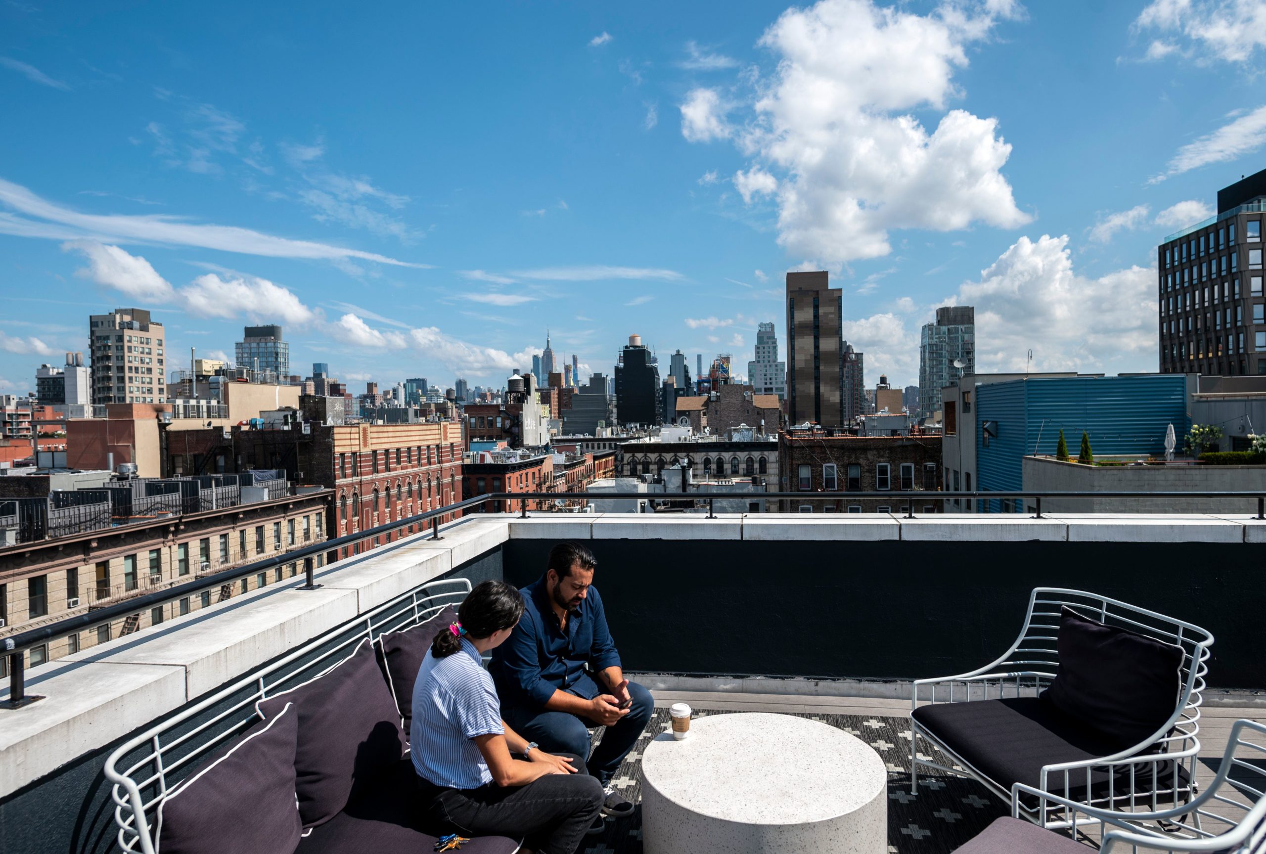 Gil Hirak (R), head of US operations and community of Quarters speaks with a colleague on the roof top of Quarters Co-Living in the Lower East Side on July 24, 2019 in New York City. - Nandita Iyer landed in New York from Bombay without knowing anyone, but she didn't want to live alone in a "sketchy studio." So instead she opted for a room in a "coliving" unit. She lives with roommates in one of the 14 apartments in a small building run by the housing start-up Quarters in the trendy Lower East Side neighborhood. The best part of the arrangement, she said, are the common areas: a large kitchen with a big table and comfy couches, a terrace where she can work and a luxurious rooftop patio. "I met people from such different backgrounds. And I became very good friends with them," she said. (Photo by Johannes EISELE / AFP) (Photo by JOHANNES EISELE/AFP via Getty Images)