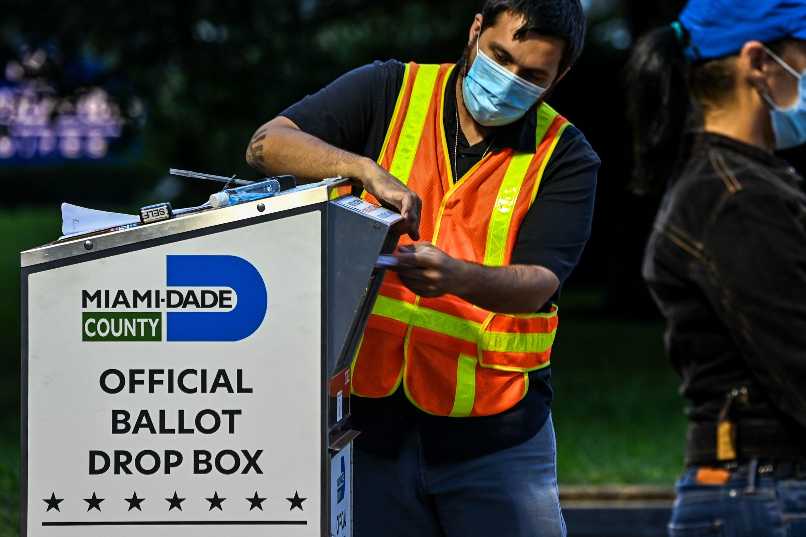 A poll worker helps a voter put as she drops off her mail-in ballot at an official Miami-Dade County drive-thru ballot drop box at the Miami-Dade County Election Department in Miami, Florida on November 3, 2020. - The US started voting Tuesday in an election amounting to a referendum on Donald Trump's uniquely brash and bruising presidency, which Democratic opponent and frontrunner Joe Biden urged Americans to end to restore "our democracy." (Photo by CHANDAN KHANNA / AFP) (Photo by CHANDAN KHANNA/AFP via Getty Images)