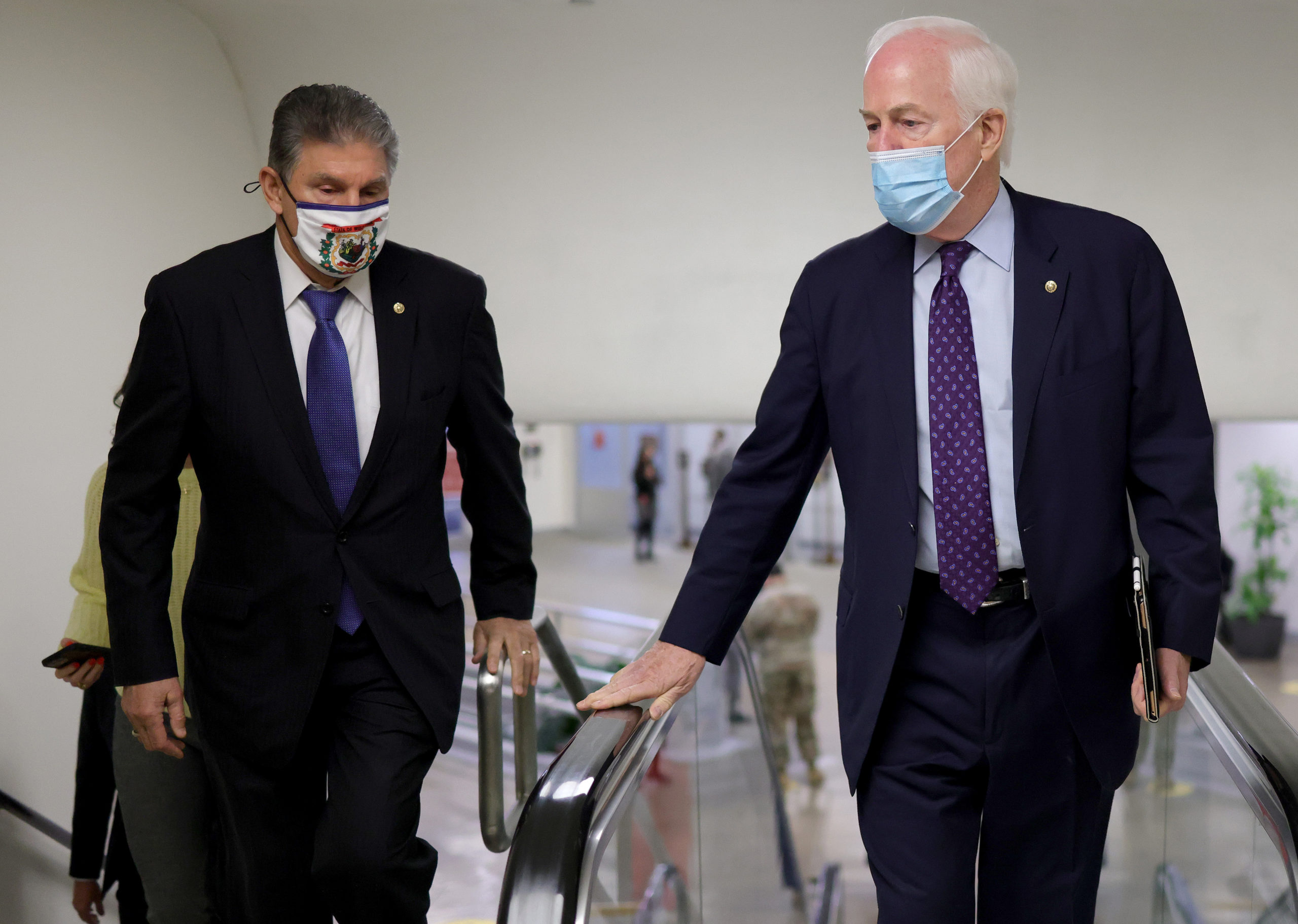 Texas Republican Sen. John Cornyn talks with West Virginia Democratic Sen. Joe Manchin while walking to the U.S. Senate chamber for a vote March 05, 2021. The Senate debated the latest COVID-19 relief bill for over 24 hours, and it passed late Saturday morning. (Win McNamee/Getty Images)