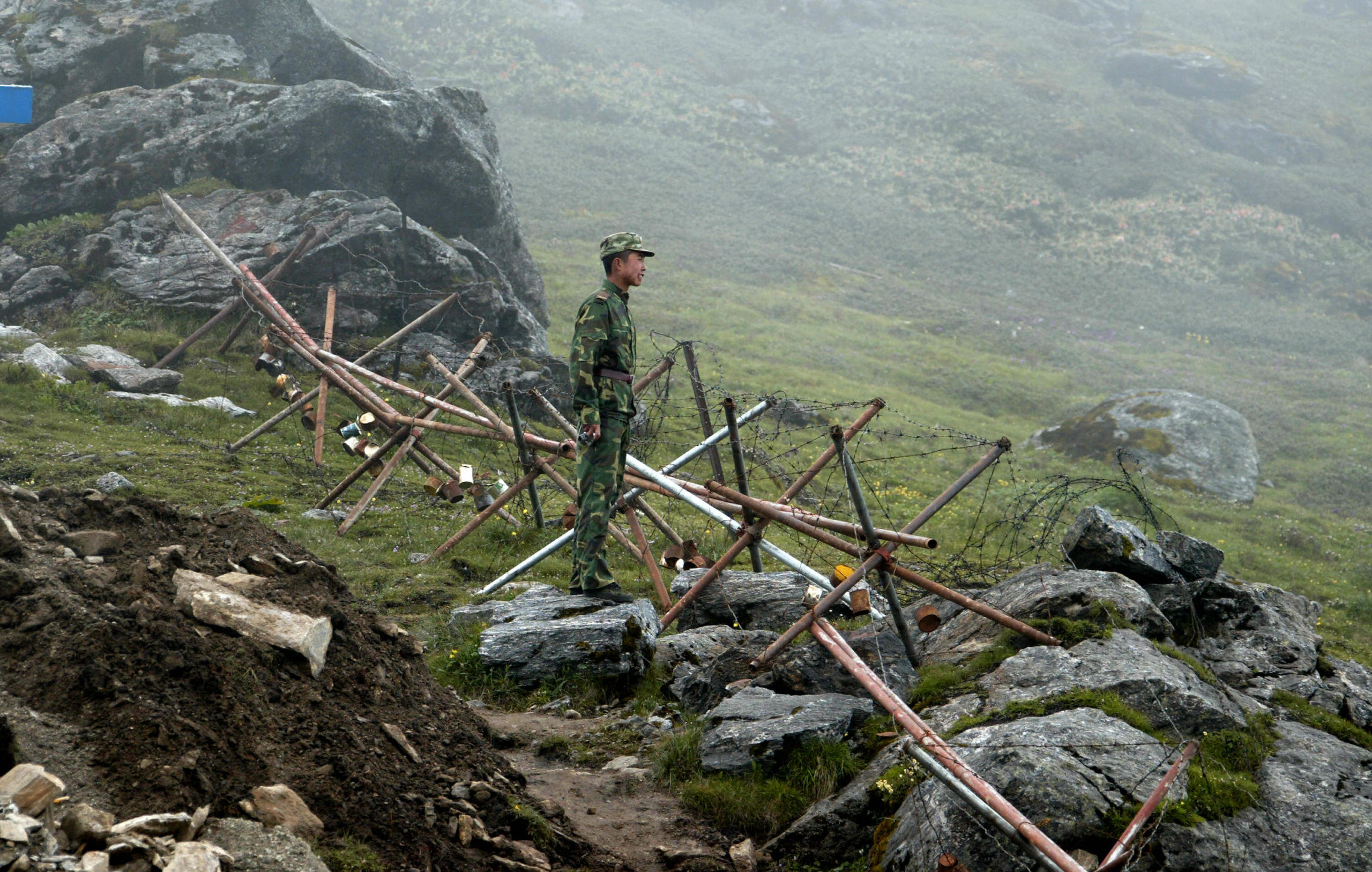 In this photograph taken on July 10, 2008, a Chinese soldier stands guard on the Chinese side of the ancient Nathu La border crossing between India and China. When the two Asian giants opened the 4,500-metre-high (15,000 feet) pass in 2006 to improve ties dogged by a bitter war in 1962 that saw the route closed for 44 years, many on both sides hoped it would boost trade. Two years on, optimism has given way to despair as the flow of traders has shrunk to a trickle because of red tape, poor facilities and sub-standard roads in India's remote northeastern mountainous state of Sikkim. AFP PHOTO/Diptendu DUTTA (Photo credit should read DIPTENDU DUTTA/AFP via Getty Images)