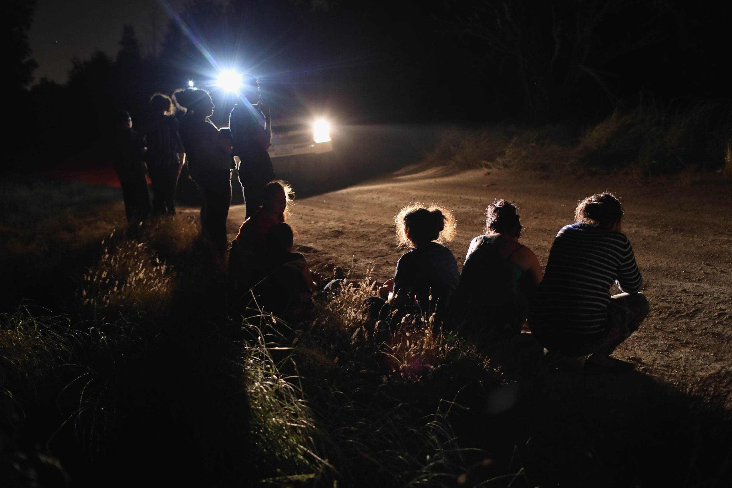 MCALLEN, TX - JUNE 12: A U.S. Border Patrol vehicle illuminates a group of Central American asylum seekers before taking them into custody near the U.S.-Mexico border on June 12, 2018 in McAllen, Texas. The group of women and children had rafted across the Rio Grande from Mexico and were detained by U.S. Border Patrol agents before being sent to a processing center for possible separation. Customs and Border Protection (CBP) is executing the Trump administration's zero tolerance policy towards undocumented immigrants. U.S. Attorney General Jeff Sessions also said that domestic and gang violence in immigrants' country of origin would no longer qualify them for political asylum status. (Photo by John Moore/Getty Images)