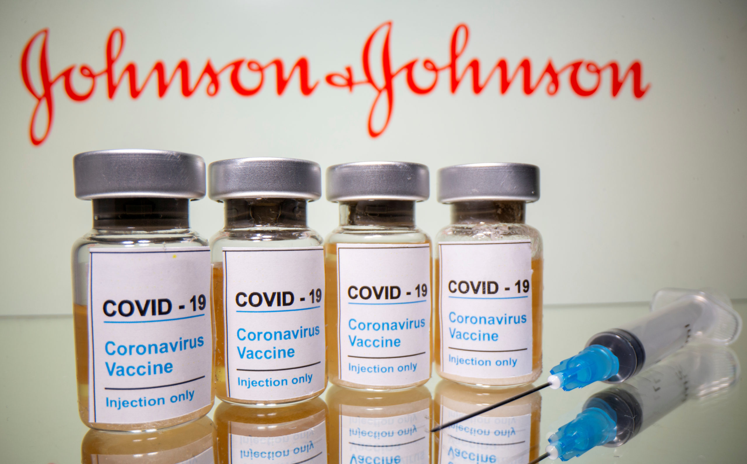 Vials with a sticker reading, "COVID-19 / Coronavirus vaccine / Injection only" and a medical syringe are seen in front of a displayed Johnson & Johnson logo in this illustration taken October 31, 2020. (REUTERS/Dado Ruvic/File Photo)