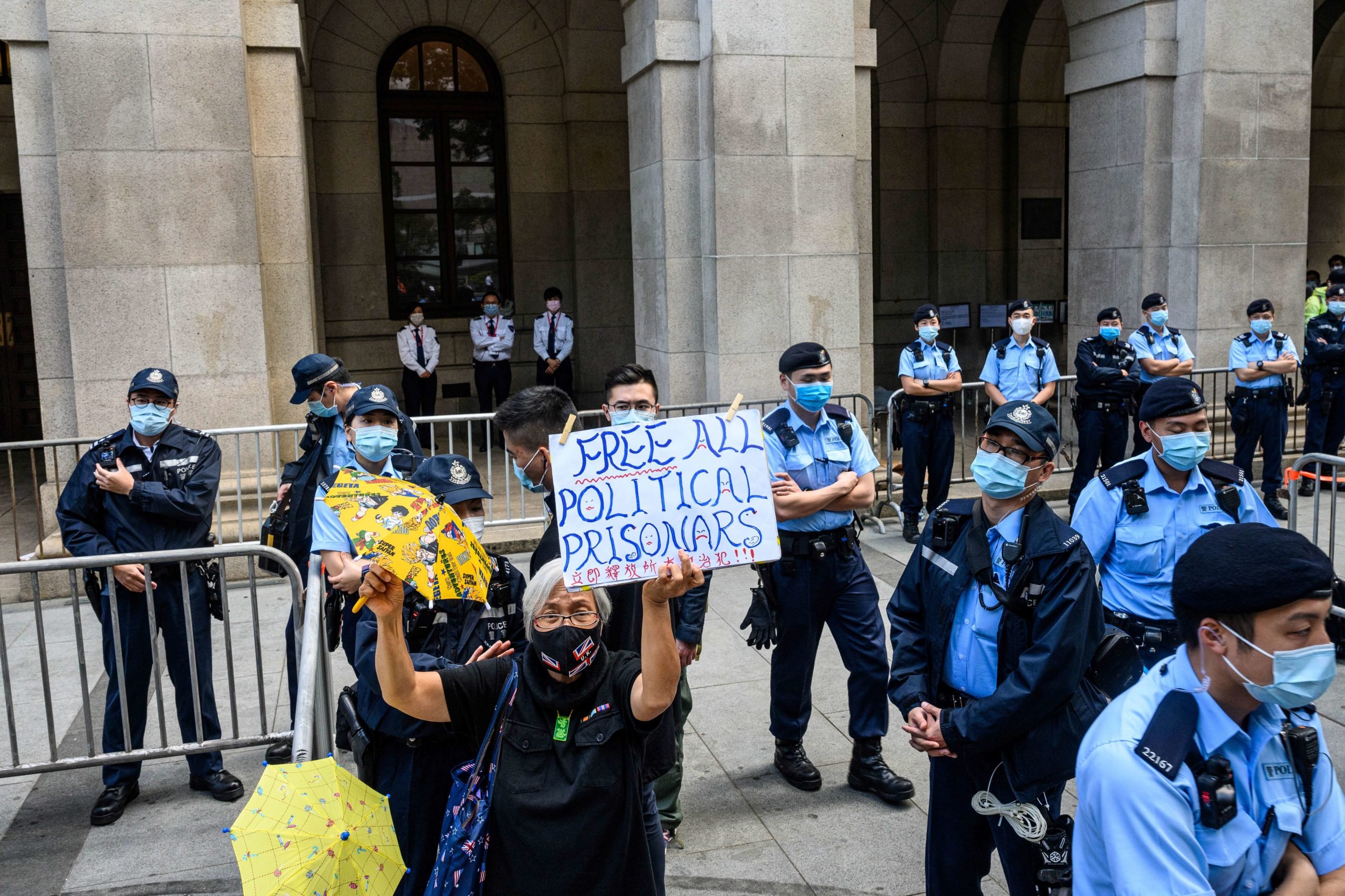 A pro-democracy activist holds up a placard as police stand guard outside the Court of Final Appeal in Hong Kong on February 1, 2021. (ANTHONY WALLACE/AFP via Getty Images)