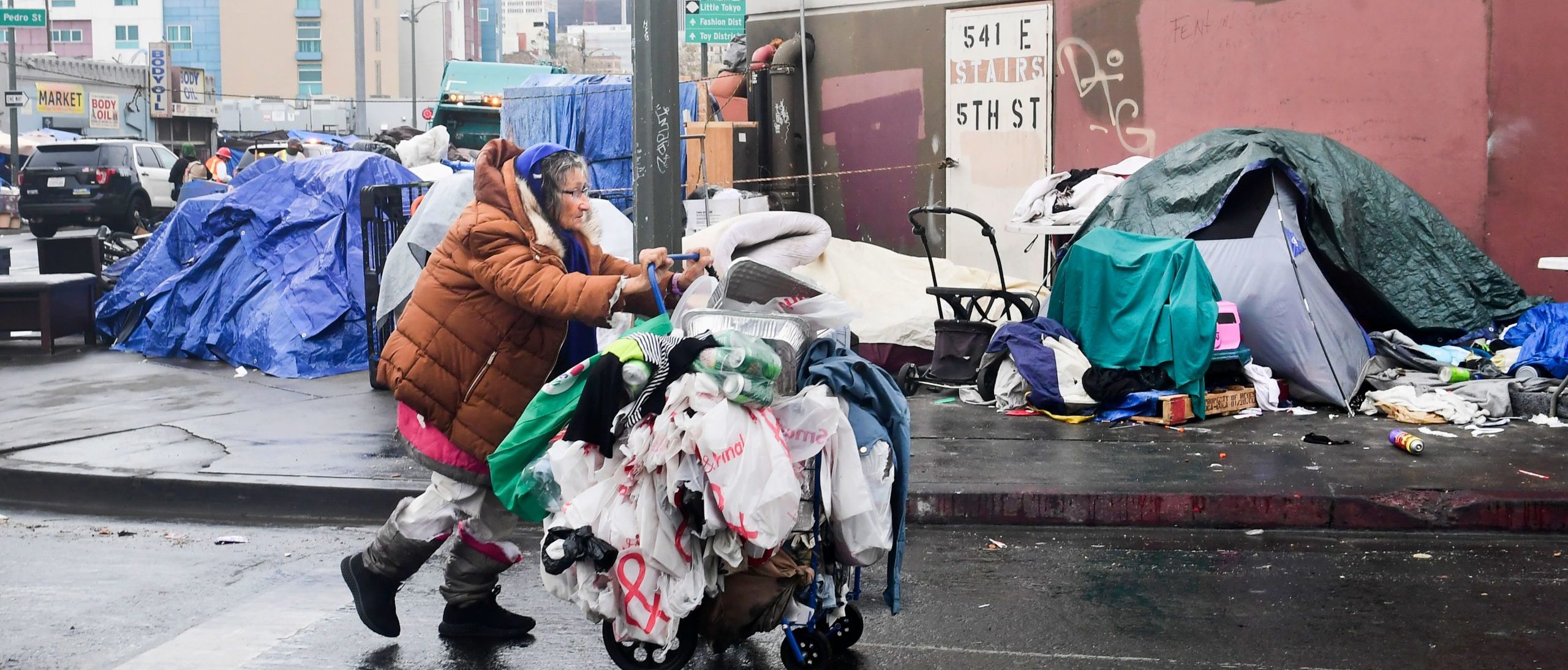A homeless woman pushes her belongings past a row of tents on the streets of Los Angeles, California on February 1, 2021. - The federal judge overseeing attempts to resolve the homeless situation has called for an urgent meeting to discuss worsening conditions and the poor official response. Combined now with the coronaviruspandemic and worsening mental health and substance abuse issues, US District Judge David Carter who toured Skid Row last week likened the situation to "a significant natural disaster in Southern California with no end in sight." (Photo by Frederic J. BROWN / AFP) (Photo by FREDERIC J. BROWN/AFP via Getty Images)