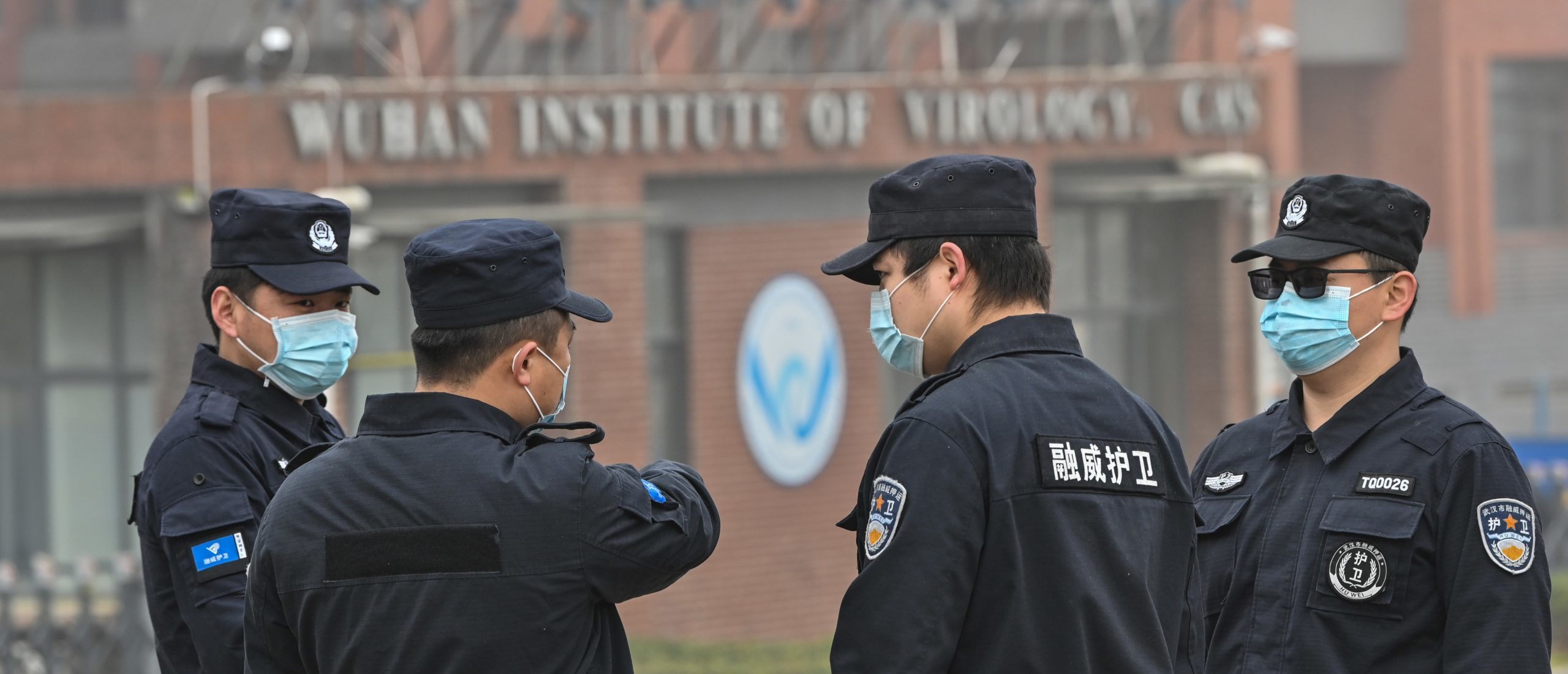 Security personnel stand guard outside the Wuhan Institute of Virology in Wuhan as members of the World Health Organization (WHO) team investigating the origins of the COVID-19 coronavirus make a visit. (Photo by HECTOR RETAMAL/AFP via Getty Images)