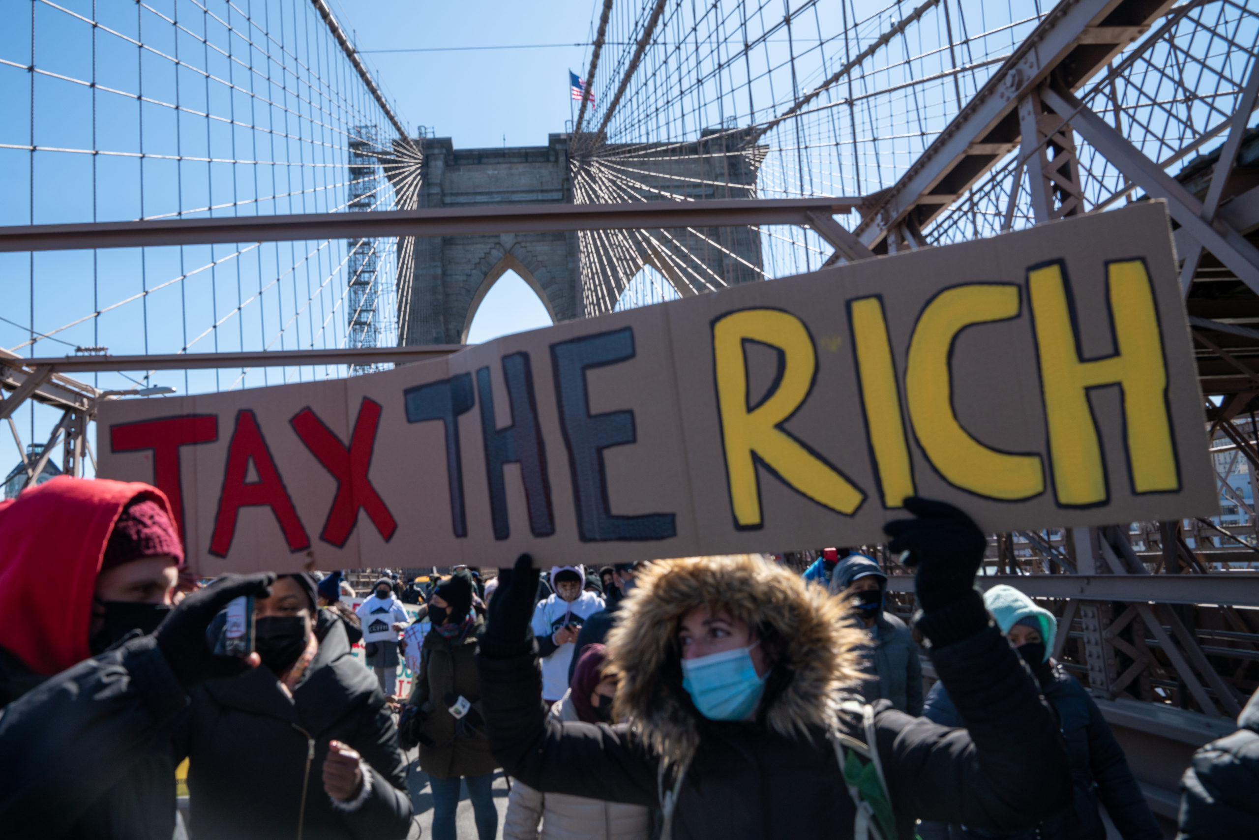 Protestors march across the Brooklyn Bridge holding a sign to "tax the rich" in March. (David Dee Delgado/Getty Images)