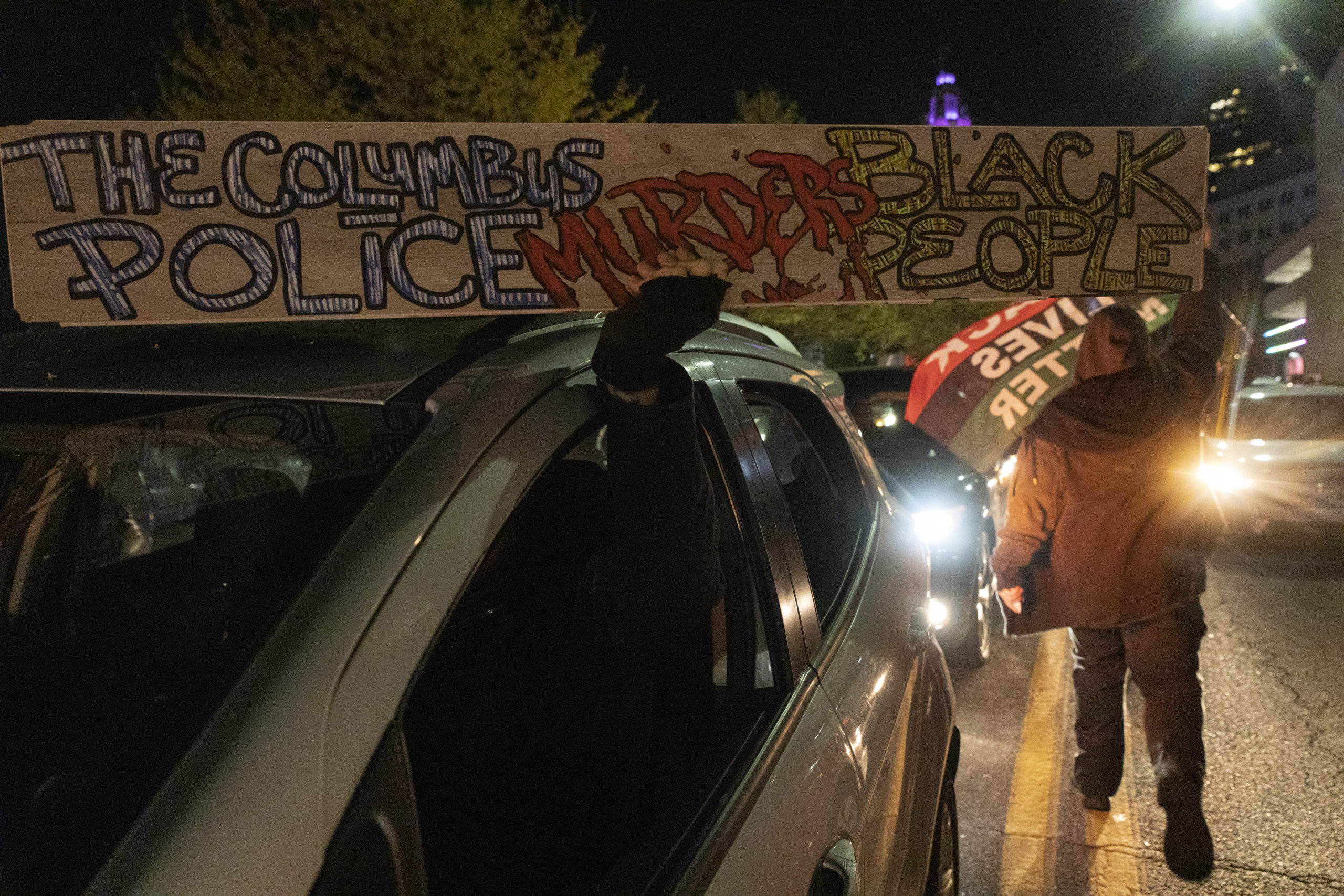 Black Lives Matter activists hold a sign condemning police brutality in Columbus during a protest in reaction to the police shooting of Ma'Khia Bryant. (Stephen Zenner/Getty Images)