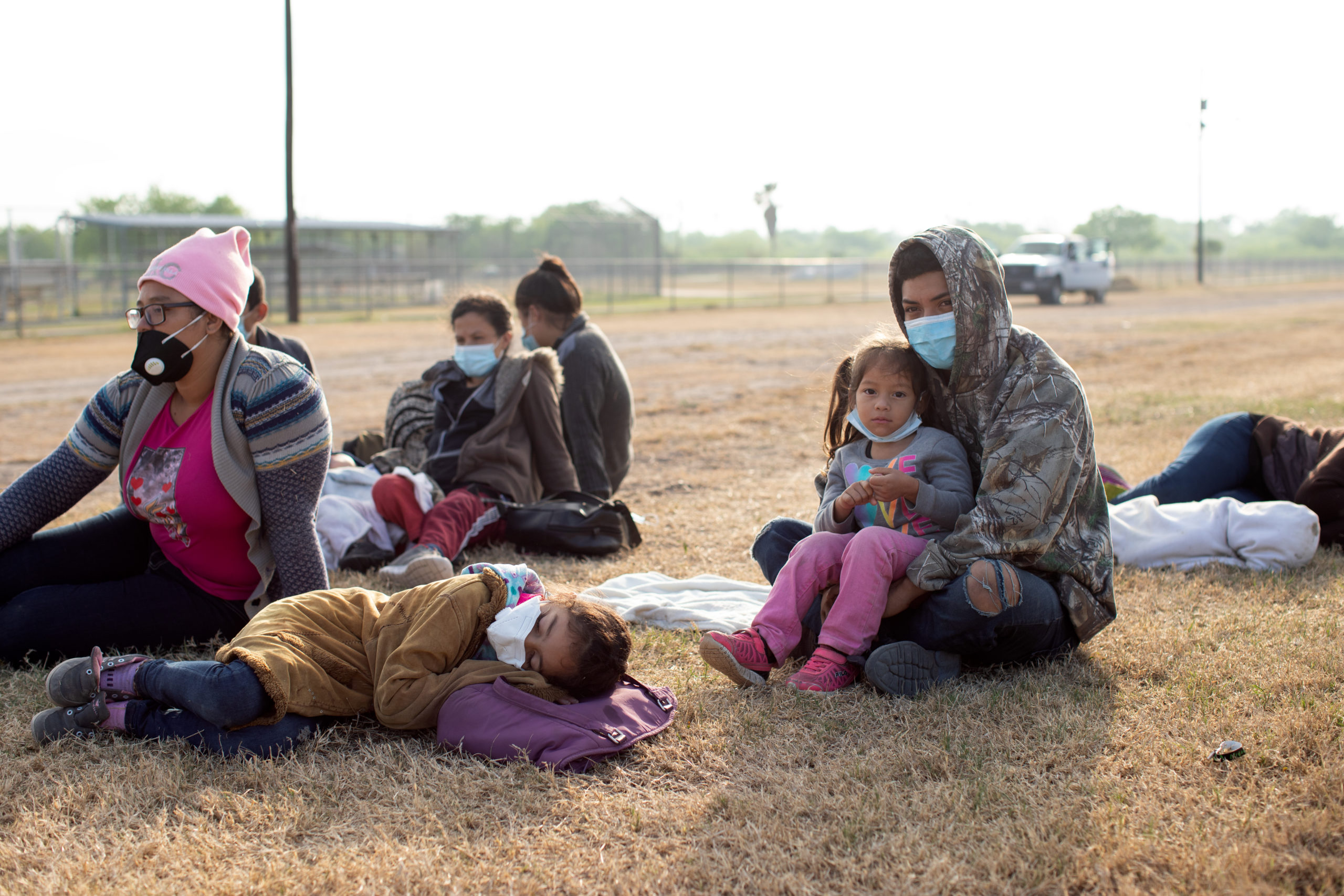 Several illegal migrants slept on the grass near the side of a public road as Customs and Border Protection officials worked to process the groups in La Joya, Texas on March 27, 2021. (Kaylee Greenlee - Daily Caller News Foundation) 