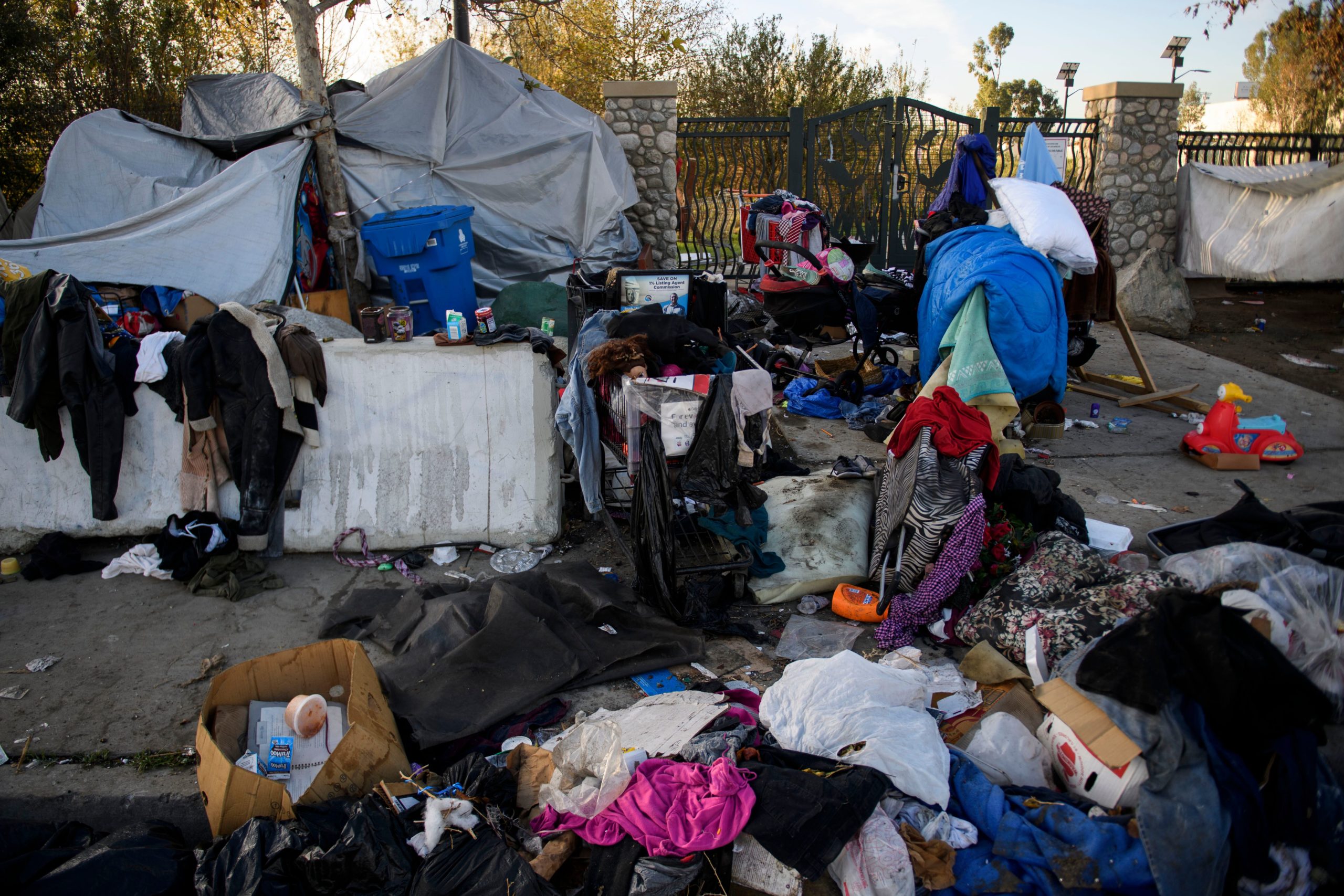 A mixture of an unhoused person's belongings and other debris covers a sidewalk outside of their shelter before Los Angeles City Sanitation workers conduct a cleanup sweep of a homeless encampment during the Covid-19 pandemic. (Photo by PATRICK T. FALLON/AFP via Getty Images)