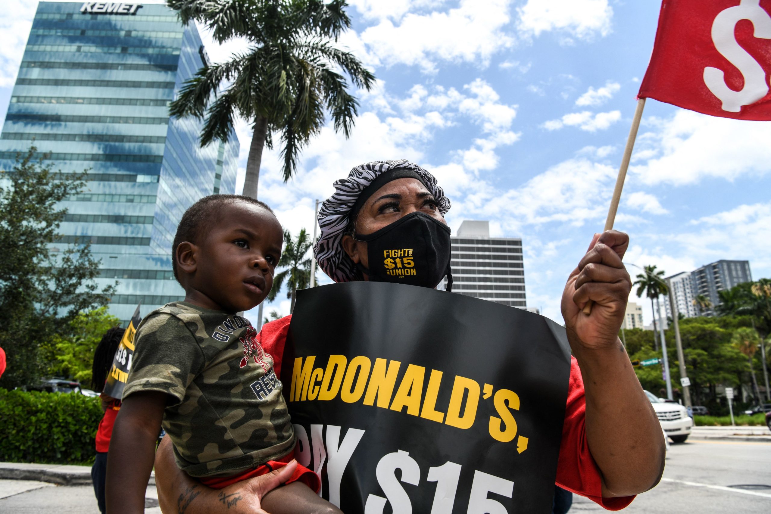Deatrice Edie holds her grandson as she protests alongside employees of McDonald's outside a branch restaurant for a raise in their minimum wage to $15 an hour, in Fort Lauderdale on May 19, 2021. - South Floridian Deatrice Edie keeps her home's belongings packed and ready to go. She hasn't paid rent in several months and expects an imminent eviction. Deatrice works three jobs, one of which is at a Fort Lauderdale McDonald's, but despite the long hours and hard labor, the 41 year old struggles to sustain her family of seven. Today she joins her coworkers in demanding a higher minimum wage. (Photo by CHANDAN KHANNA / AFP) (Photo by CHANDAN KHANNA/AFP via Getty Images)