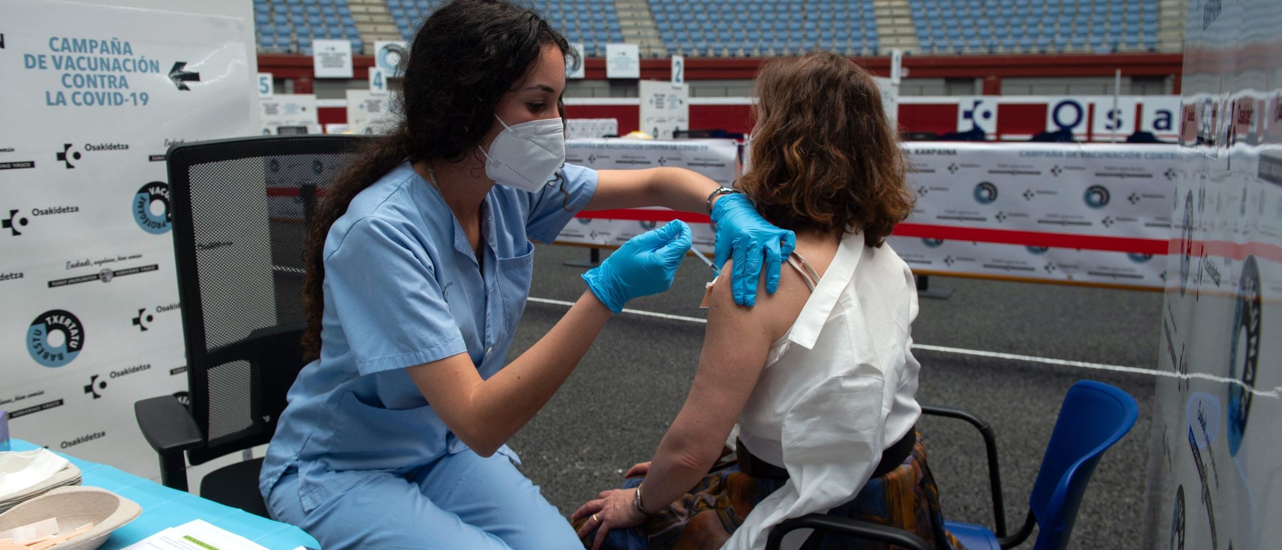 A health worker inoculates a woman with a vaccine against Covid-19 at the Donostia Arena former bullring in San Sebastian on May 31, 2021. (Photo by ANDER GILLENEA/AFP via Getty Images)