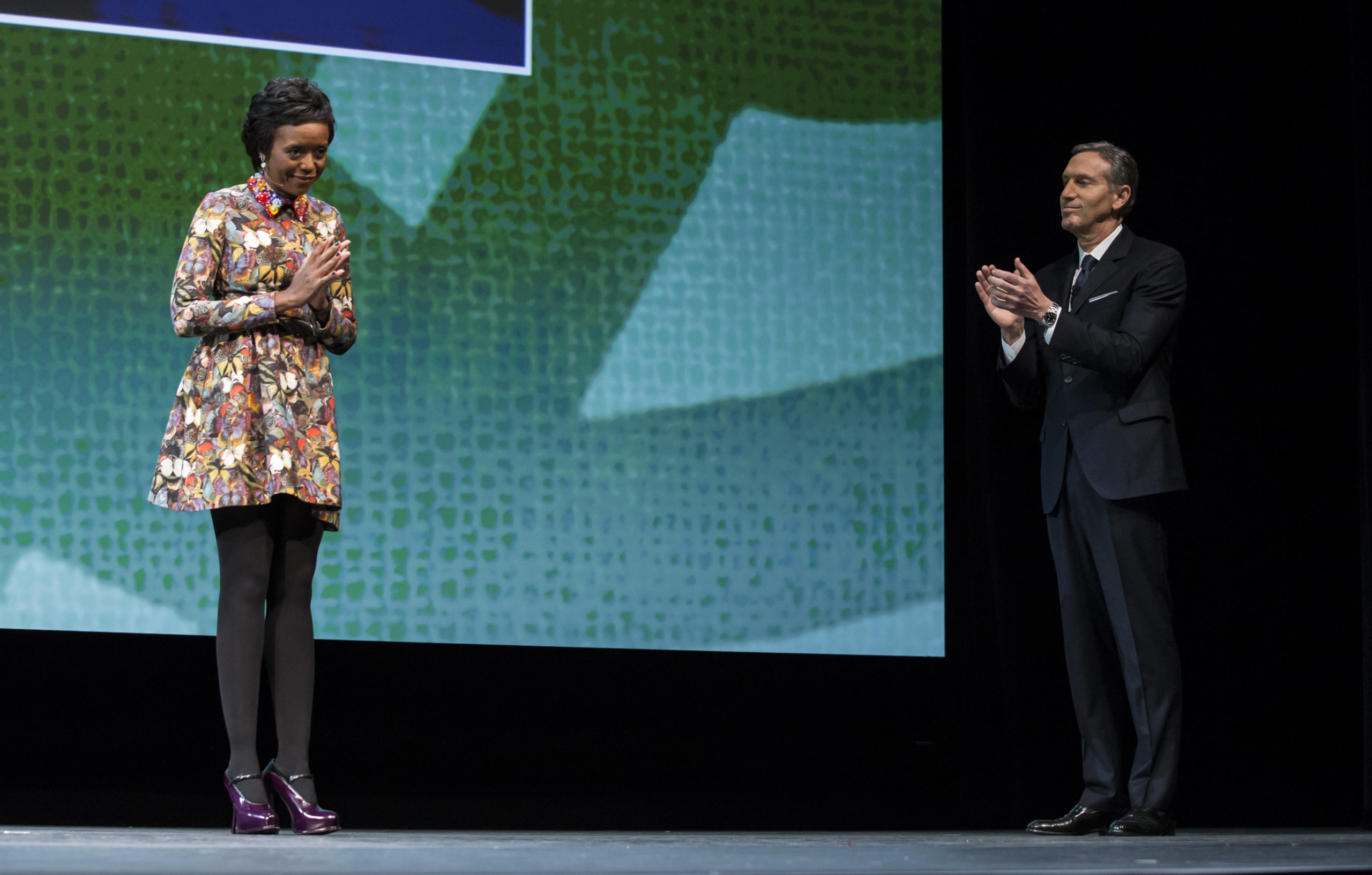 Starbucks board member Melody Hobson bows while former CEO Howard Schultz applauds at the Starbucks annual shareholders meeting on March 18, 2015 in Seattle, Washington. (Stephen Brashear/Getty Images)