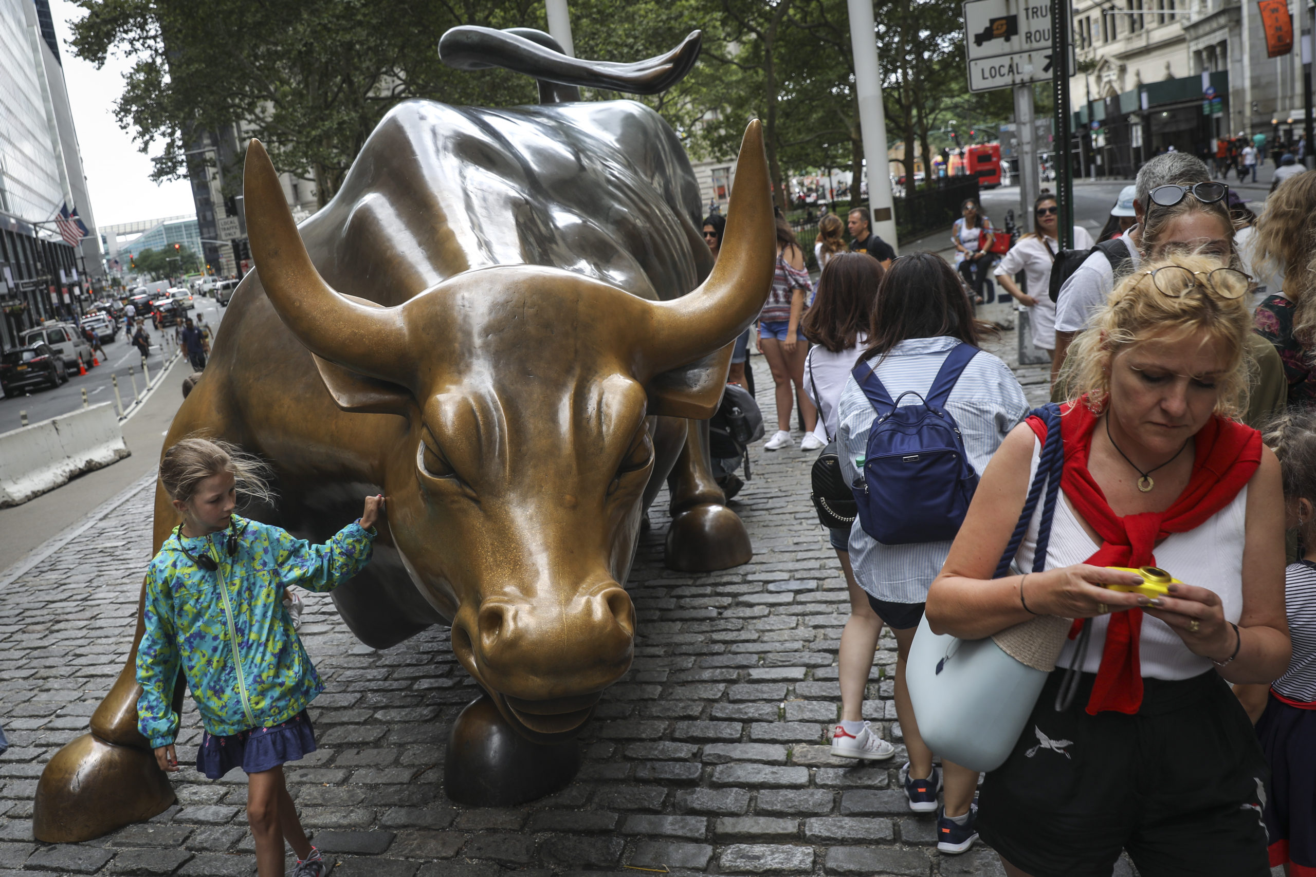 Tourists visit the Wall Street bull statue in the Financial District in New York City. (Photo by Drew Angerer/Getty Images)