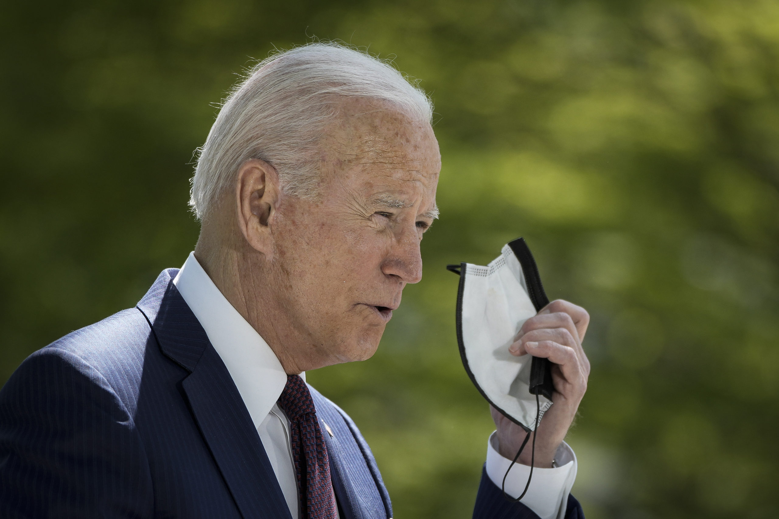 WASHINGTON, DC - APRIL 27: U.S. President Joe Biden removes his mask before speaking about updated CDC mask guidance on the North Lawn of the White House on April 27, 2021 in Washington, DC. President Biden announced updated CDC guidance, saying vaccinated Americans do not need to wear a mask outside when in small groups. (Photo by Drew Angerer/Getty Images)