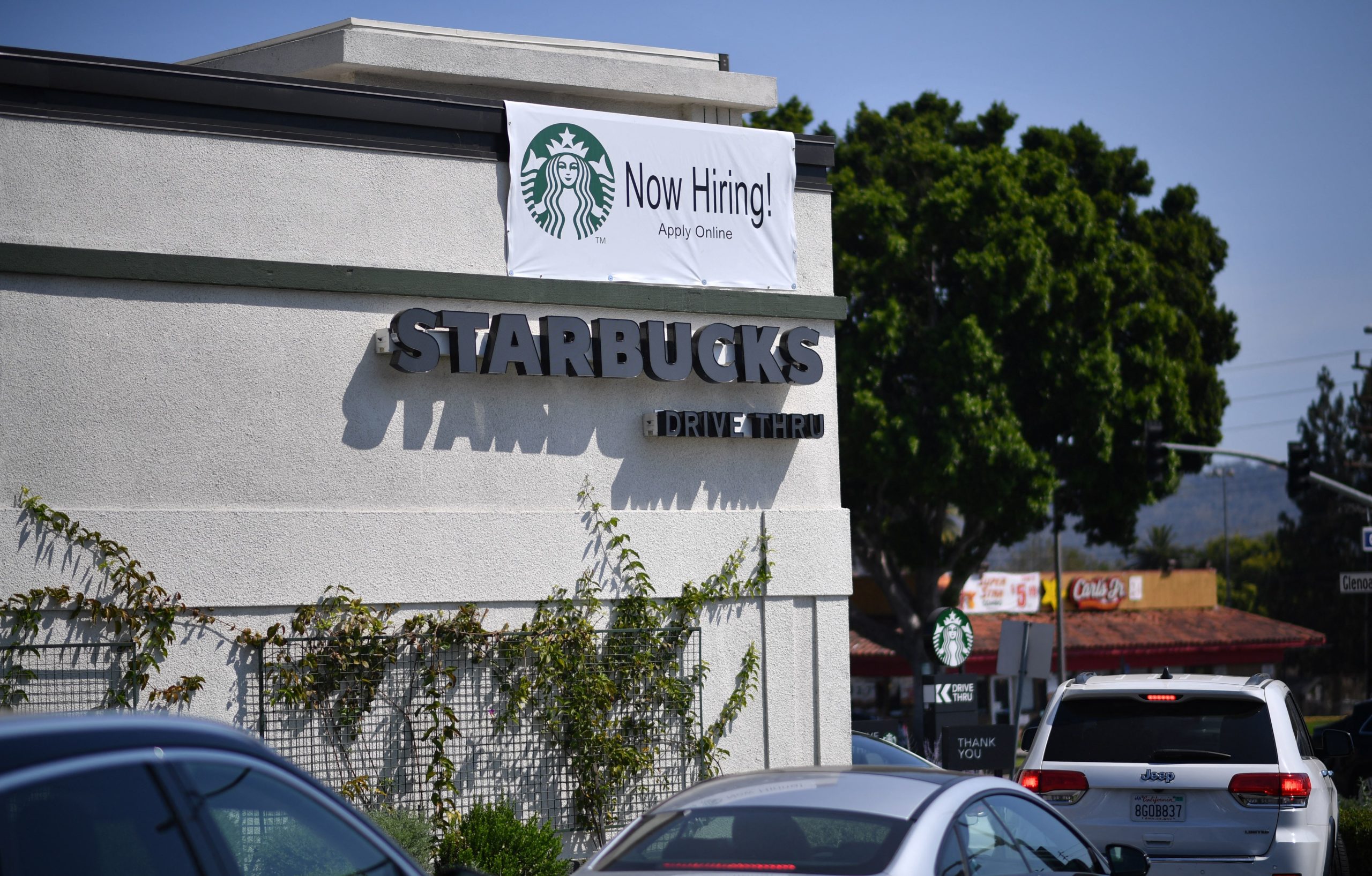 A "Now Hiring" sign is displayed outside a Starbucks drive-thru in Glendale, California. (Robyn Beck/AFP via Getty Images)
