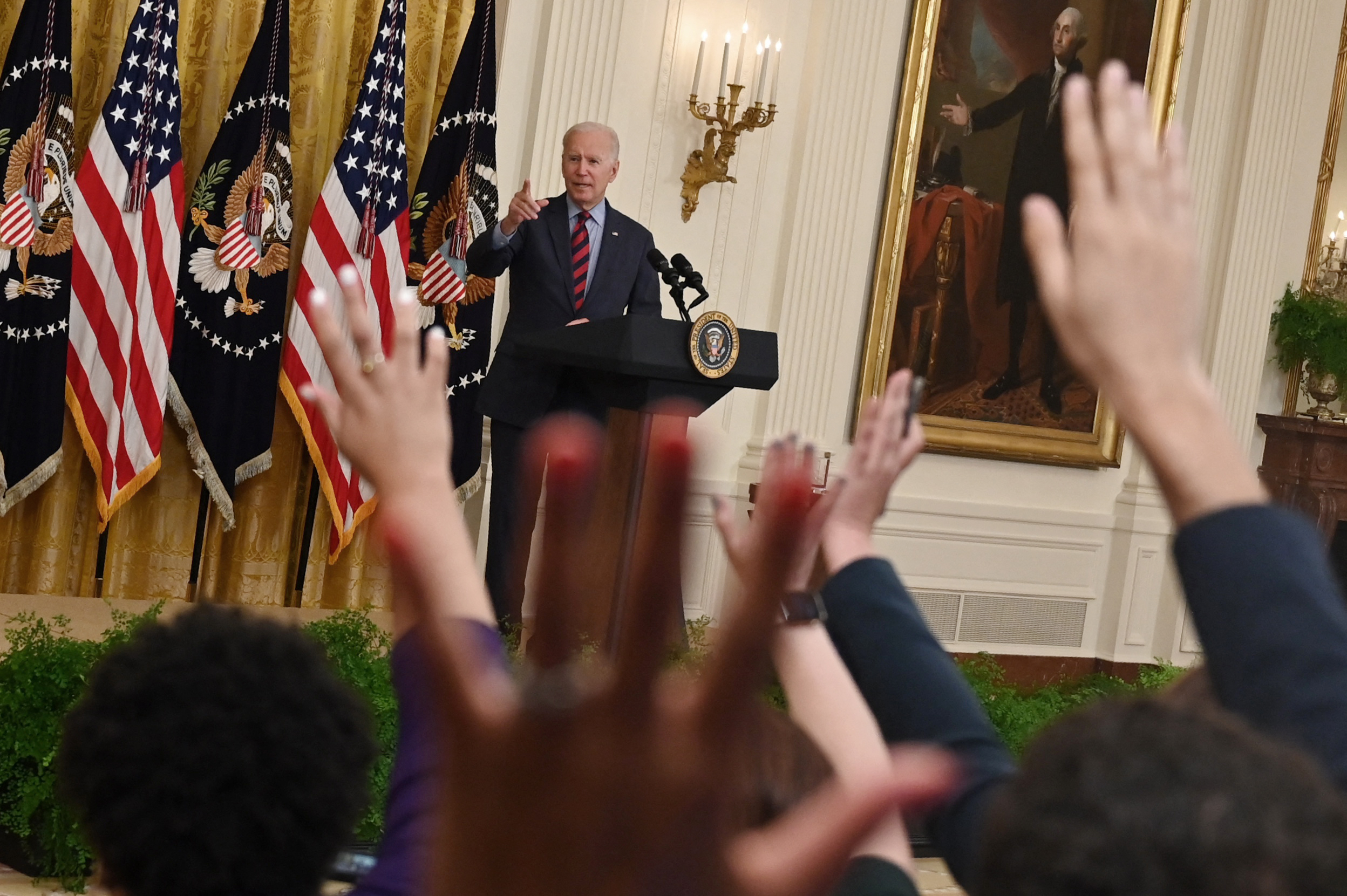 Reporters raise their hands after President Joe Biden speaks about vaccinations and the economy Tuesday. (Jim Watson/AFP via Getty Images)