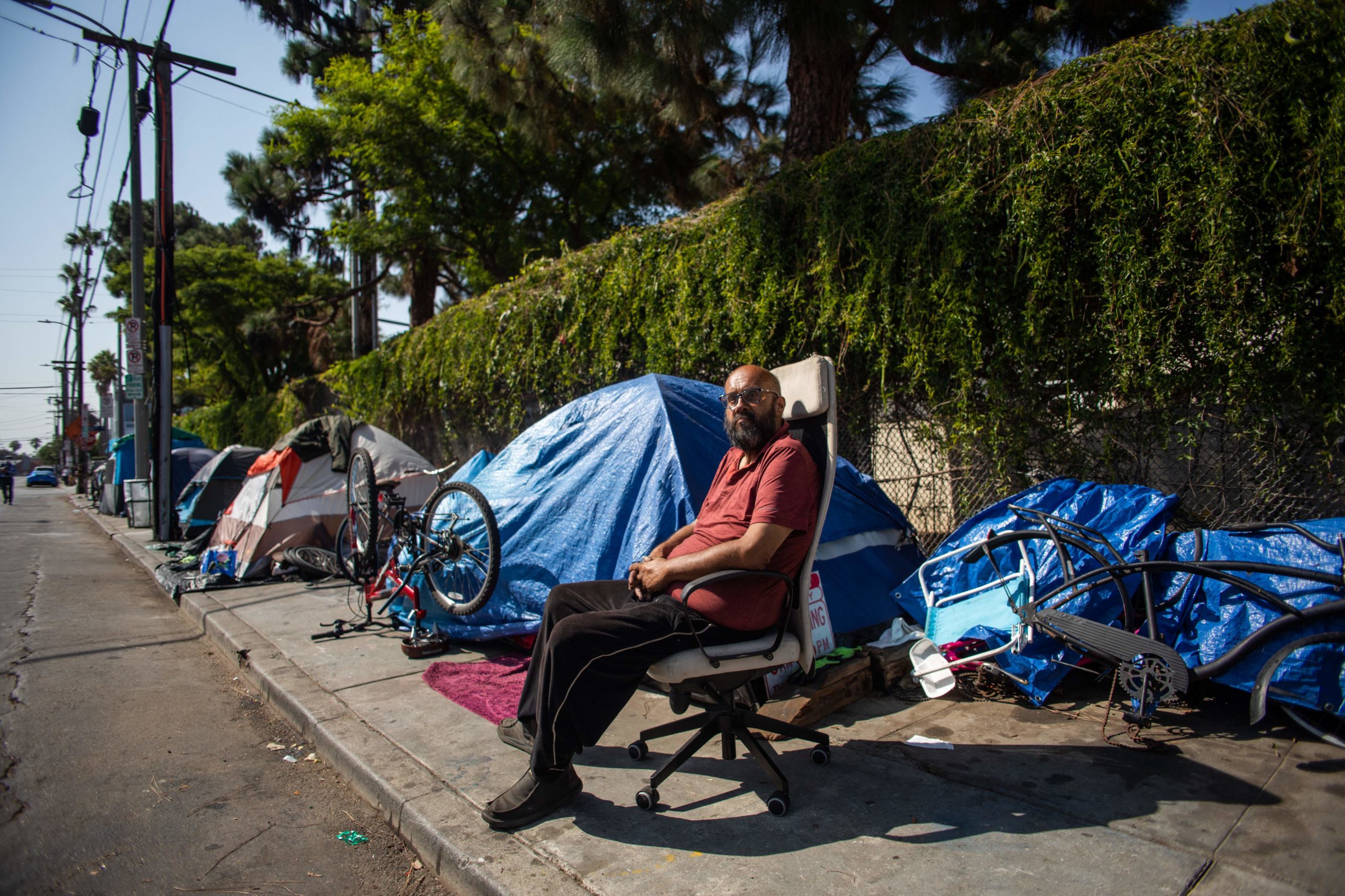 A homeless man sits outside his tent on a sidewalk in Venice Beach, California on Aug. 12. (Apu Gomes/AFP via Getty Images)
