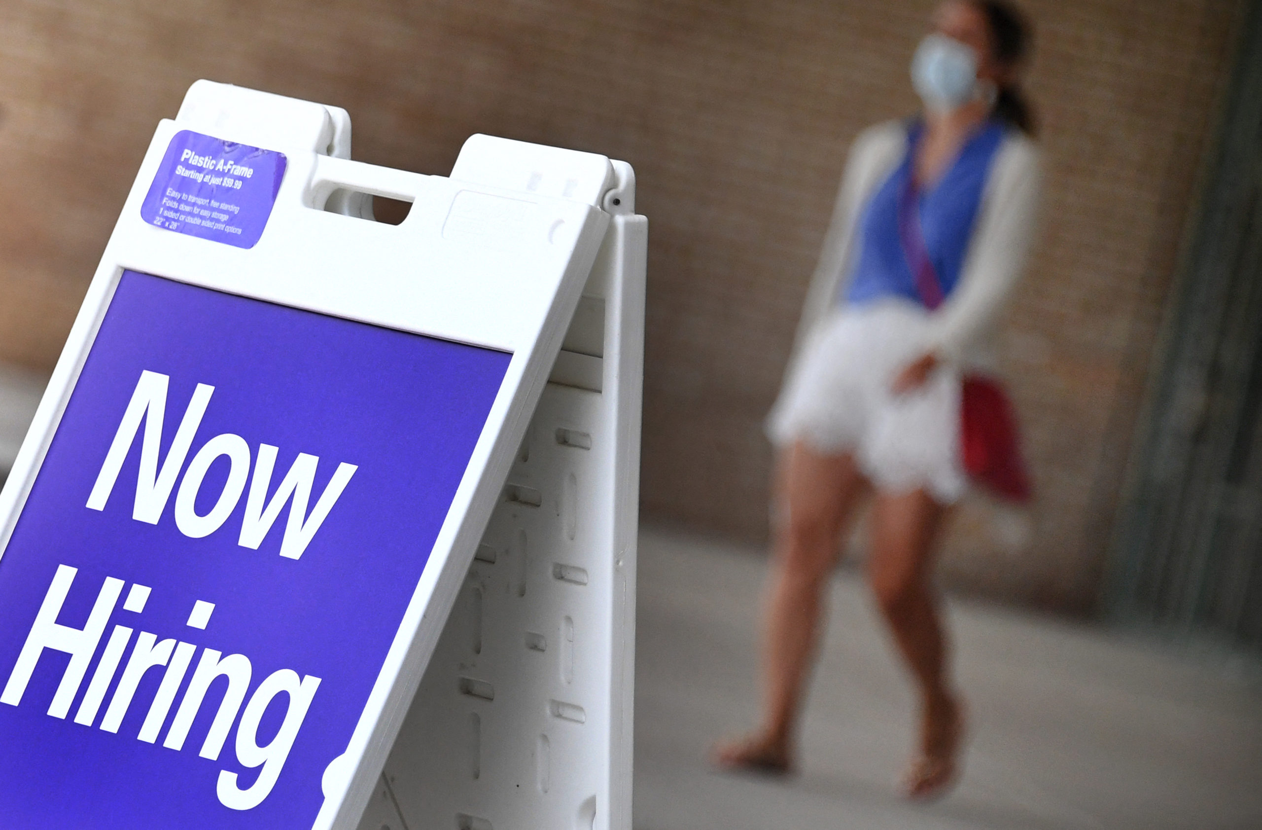 Pedestrians walk by a "Now Hiring" sign outside a store in Arlington, Virginia on Aug. 16. (Olivier Douliery/AFP via Getty Images)