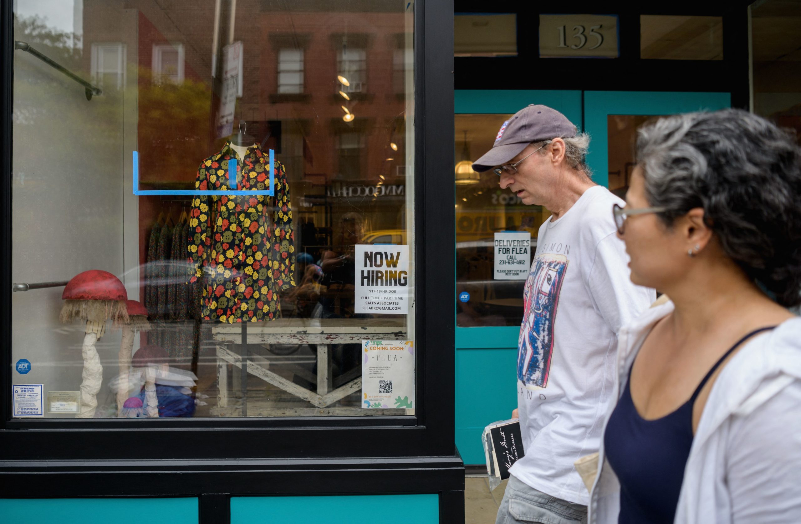 Two people walk past a 'now hiring' sign posted at a store in New York City on Aug. 20. (Angela Weiss/AFP via Getty Images)
