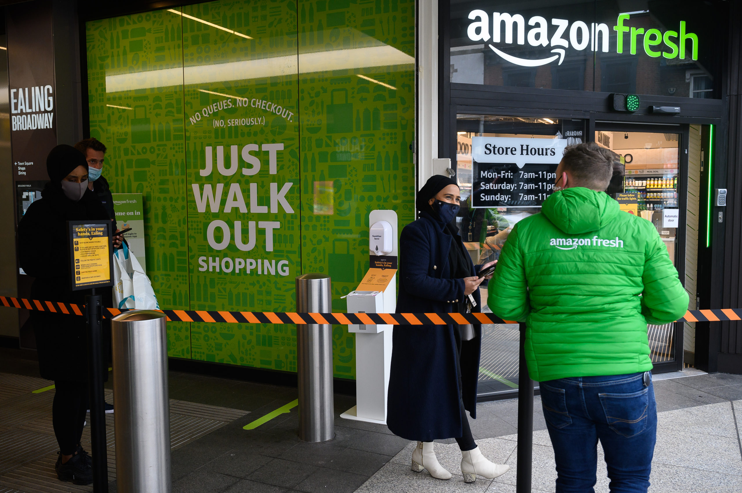Members of staff assist customers as they wait to enter an Amazon Fresh on March 4. (Leon Neal/Getty Images)