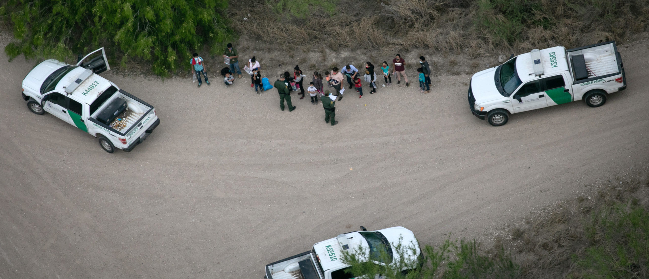 MCALLEN, TEXAS - MARCH 23: U.S. Border Patrol agents take asylum seekers into custody as seen from a Texas Department of Public Safety helicopter near the U.S.-Mexico Border on March 23, 2021 in McAllen, Texas. Texas DPS troopers are taking part in Operation Lone Star in supporting U.S. Border Patrol agents to "deny Mexican Cartels and other smugglers the ability to move drugs and people into Texas." (Photo by John Moore/Getty Images)
