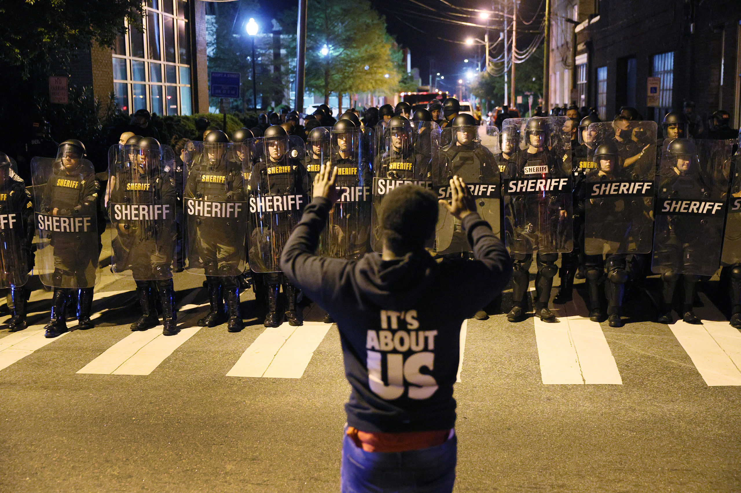 A protester stands with his arms raised as law enforcement officials in riot gear force people off a street on April 28 in Elizabeth City, North Carolina. (Joe Raedle/Getty Images)