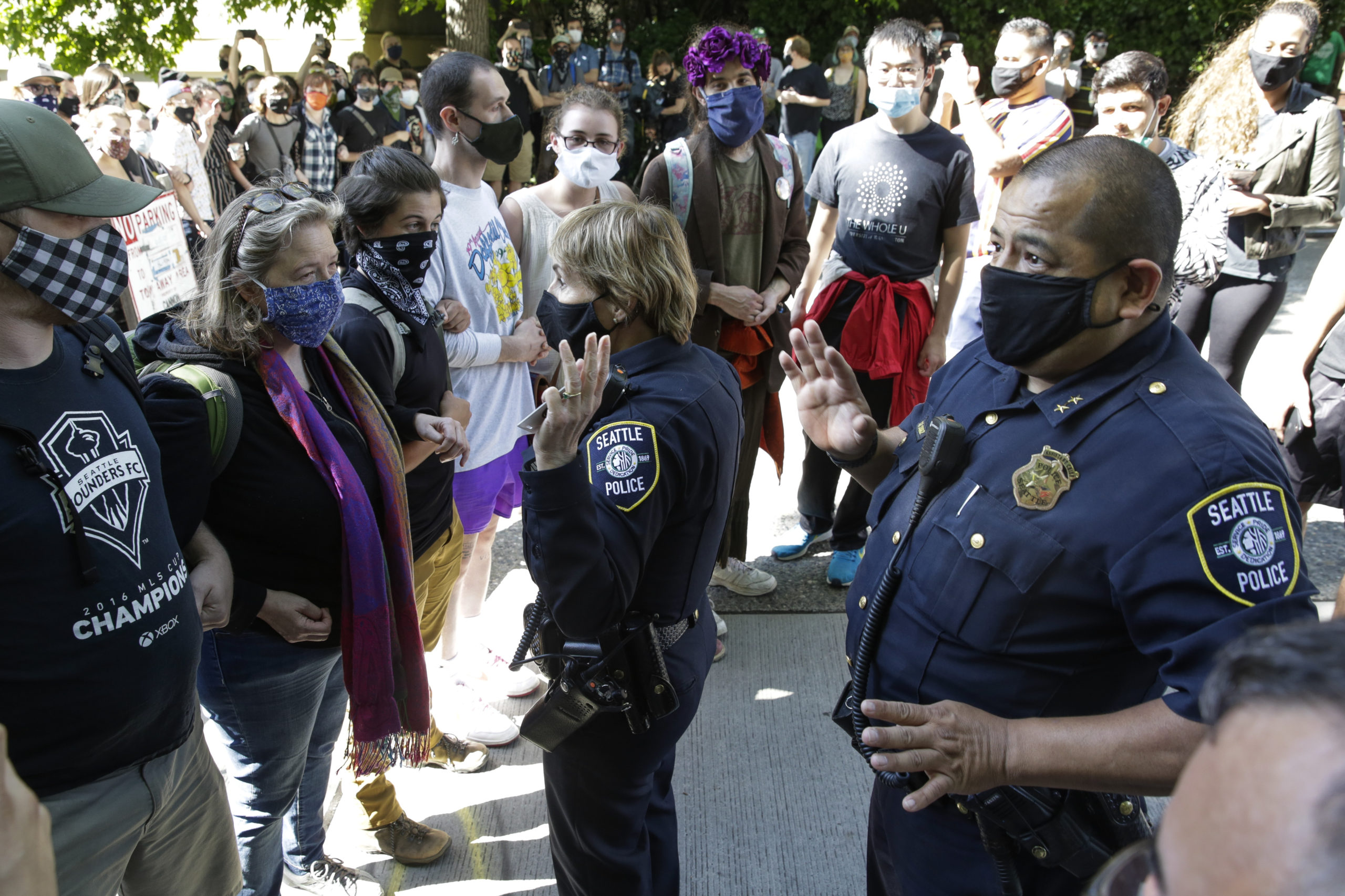 TOPSHOT - Seattle Police Assistant Chief Deanna Nollette and Assistant Chief Adrian Diaz are blocked by protesters from entering the newly created Capitol Hill Autonomous Zone (CHAZ) in Seattle, Washington on June 11, 2020. - Two police officers attempt to enter the area, but are blocked by people standing close together and holding cameras as they film. The area surrounding the East Precinct building has come to be known as the CHAZ, Capitol Hill Autonomous Zone. (Photo by Jason Redmond / AFP) (Photo by JASON REDMOND/AFP via Getty Images)