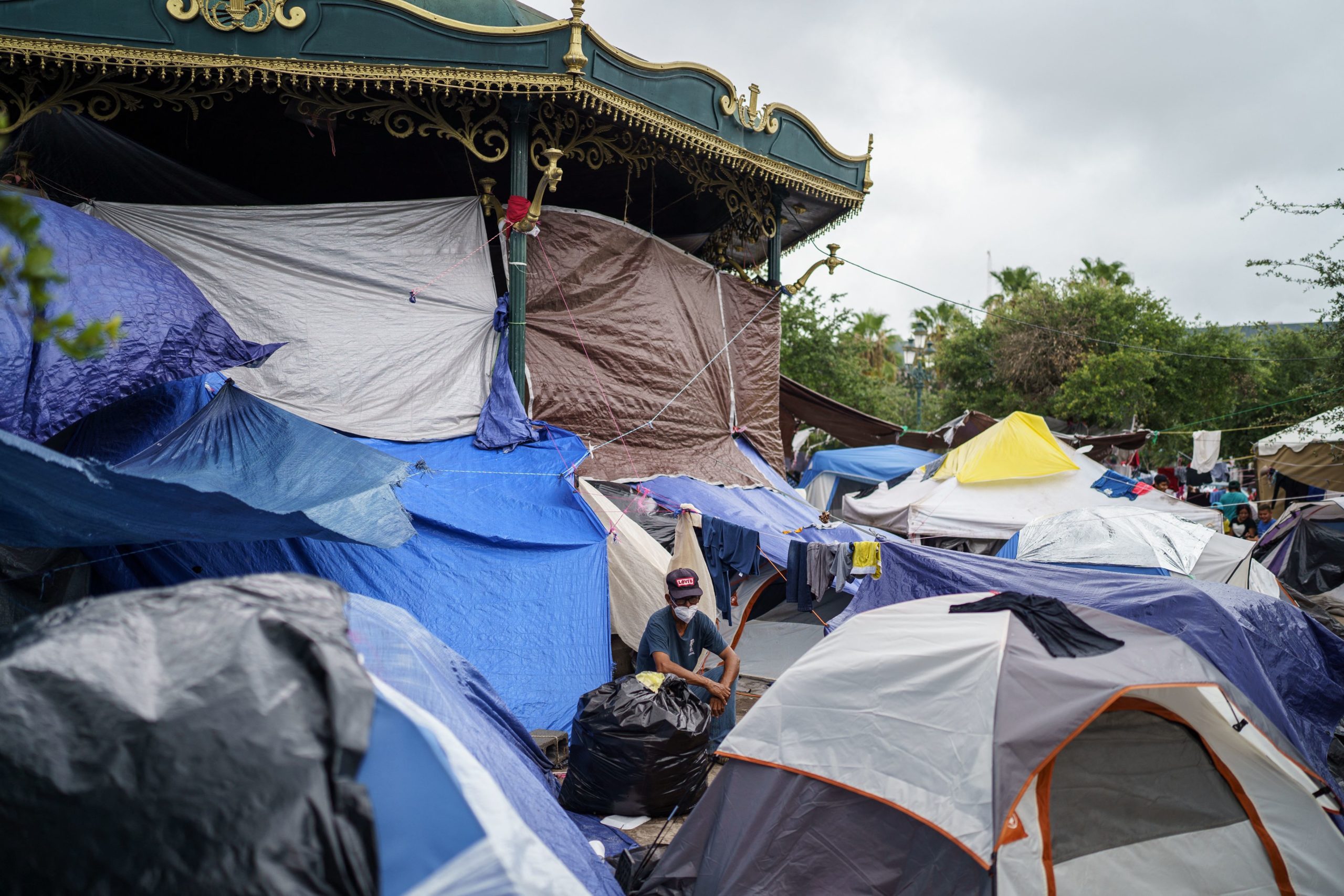 A man sits among a sea of tents in a makeshift migrant camp in the border town of Reynosa, Tamaulipas, Mexico on July 10, 2021. (Photo by PAUL RATJE/AFP via Getty Images)