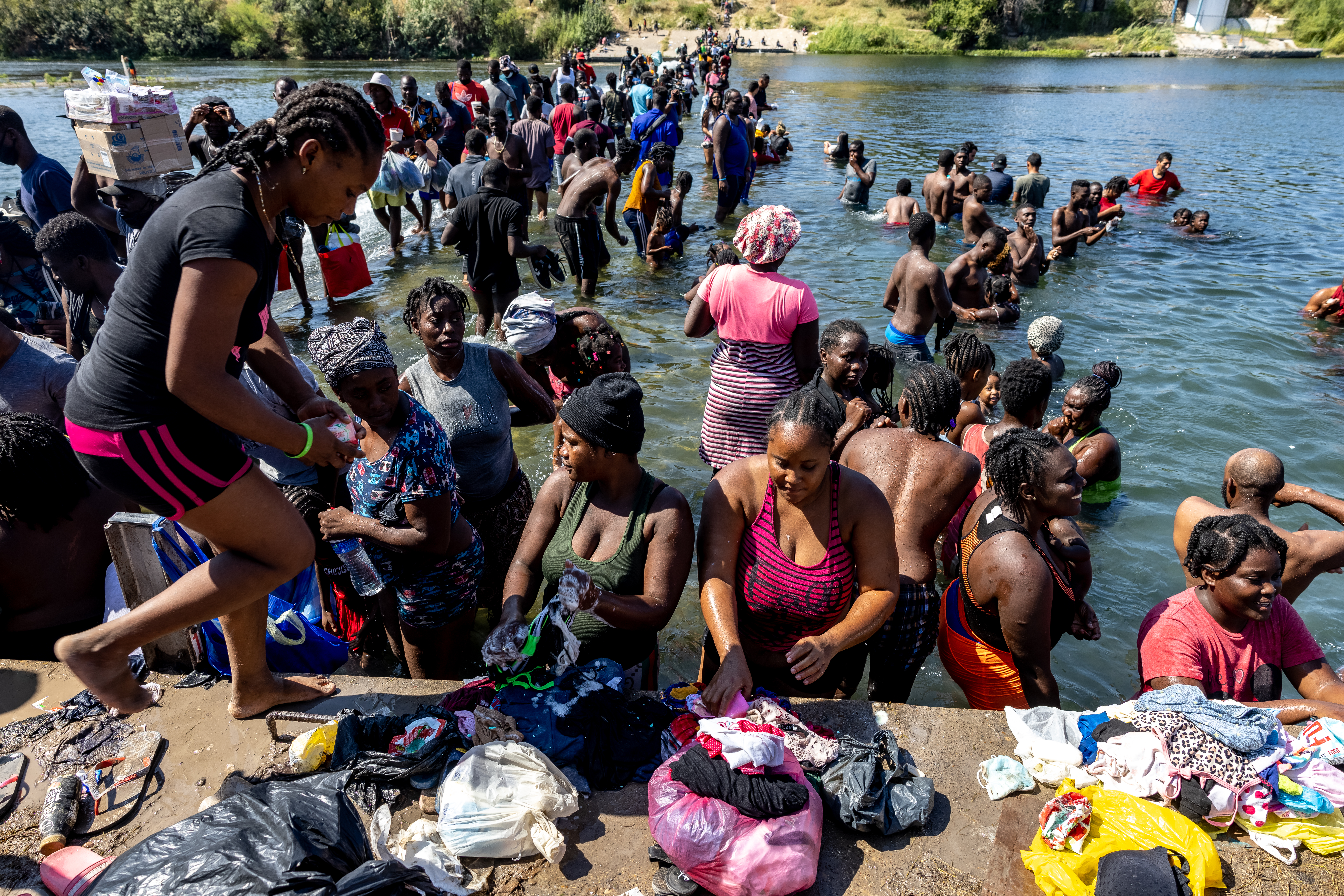 Migrants wash their clothes in the Rio Grande River near a makeshift encampment under the International Bridge between Del Rio, TX and Acuña, MX on September 17, 2021 in Del Rio, Texas. (Photo by Jordan Vonderhaar/Getty Images)