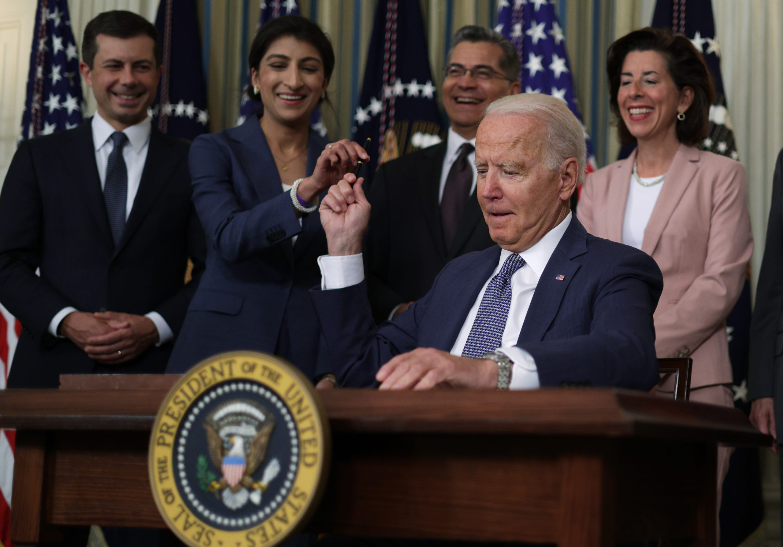 President Joe Biden passes a pen to FTC Chair Lina Khan at the White House on July 9. (Alex Wong/Getty Images)