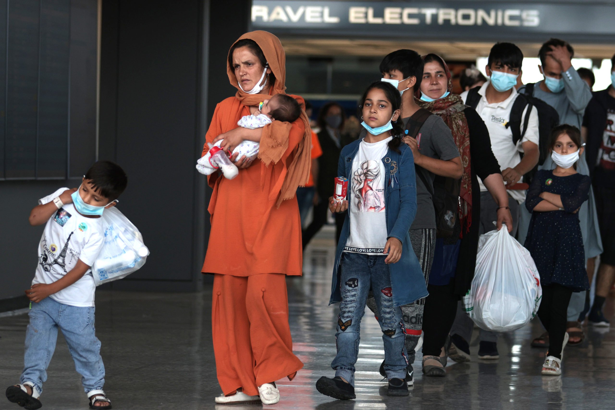 Refugees walk through the departure terminal to a bus at Dulles International Airport after being evacuated from Kabul following the Taliban takeover of Afghanistan on August 31, 2021 in Dulles, Virginia. (Photo by Anna Moneymaker/Getty Images)