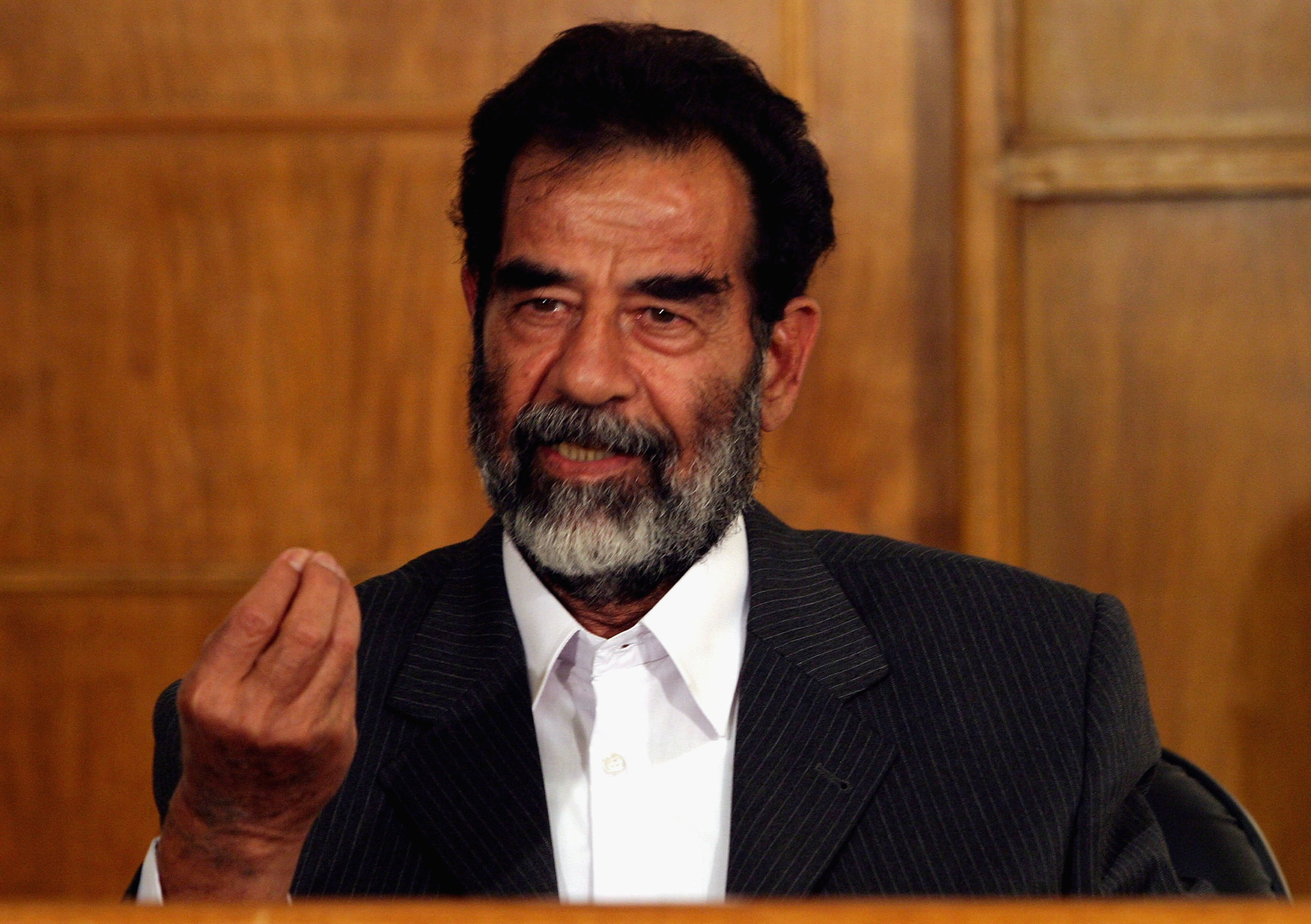 BAGHDAD, IRAQ - JULY 1: Former Iraqi President Saddam Hussein gestures as he responds to a as a list of charges that he and 11 other high level defendents are facing in an Iraqi courtroom July 1, 2004 in Baghdad, Iraq. Hussein was transferred into the legal custody of Iraqi authorities on June 30, 2004 but remains in the physical custody of the U.S. Military at an undisclosed location. Hussein is not expected to face trial in an Iraqi court for at least several months. (Photo by Karen Ballard/Pool - Getty Images)