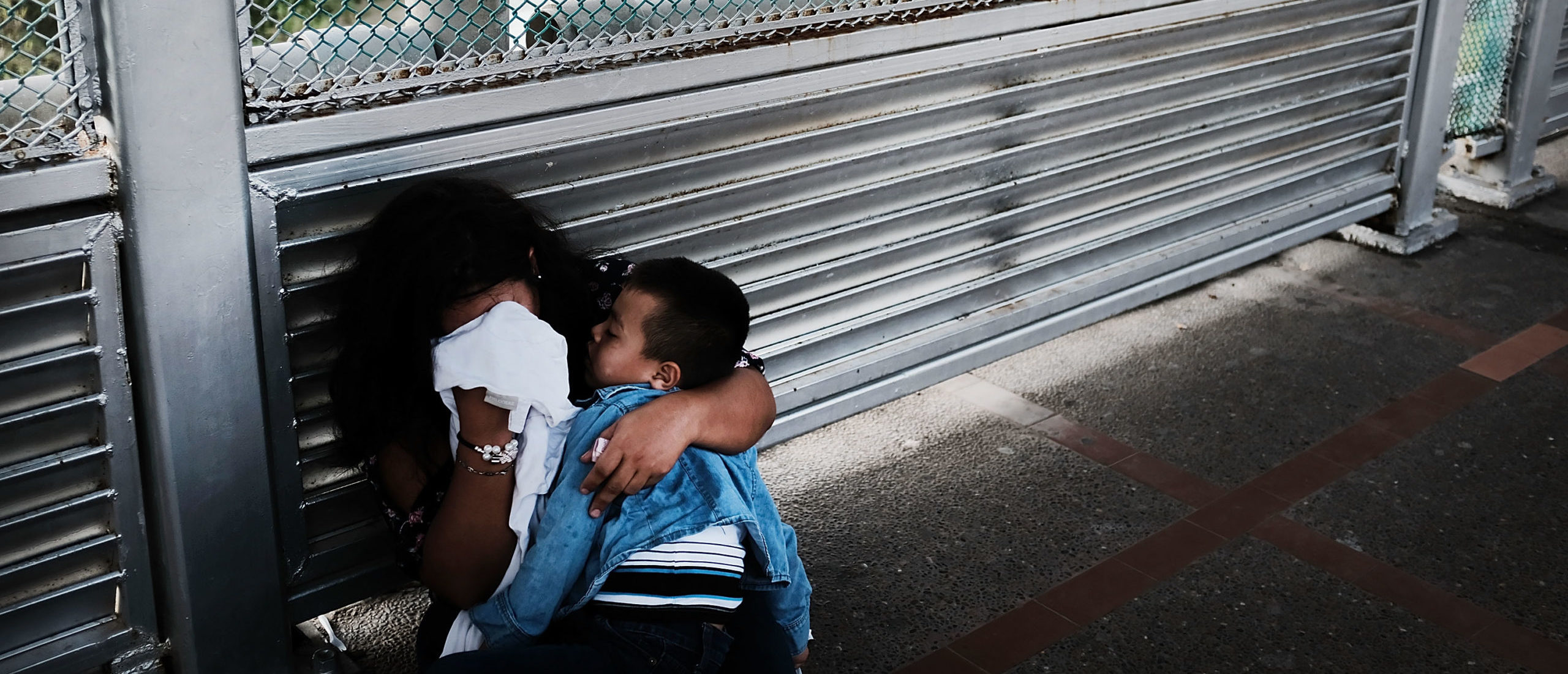 BROWNSVILLE, TX - JUNE 22: A crying Honduran woman and her child wait along the border bridge after being denied into the Texas city of Brownsville which has become dependent on the daily crossing into and out of Mexico on June 22, 2018 in Brownsville, Texas. Immigration has once again been put in the spotlight as Democrats and Republicans spar over the detention of children and families seeking asylum at the border. Before President Donald Trump signed an executive order Wednesday that halts the practice of separating families who were seeking asylum, over 2,300 immigrant children had been separated from their parents in the zero-tolerance policy for border crossers. (Photo by Spencer Platt/Getty Images)