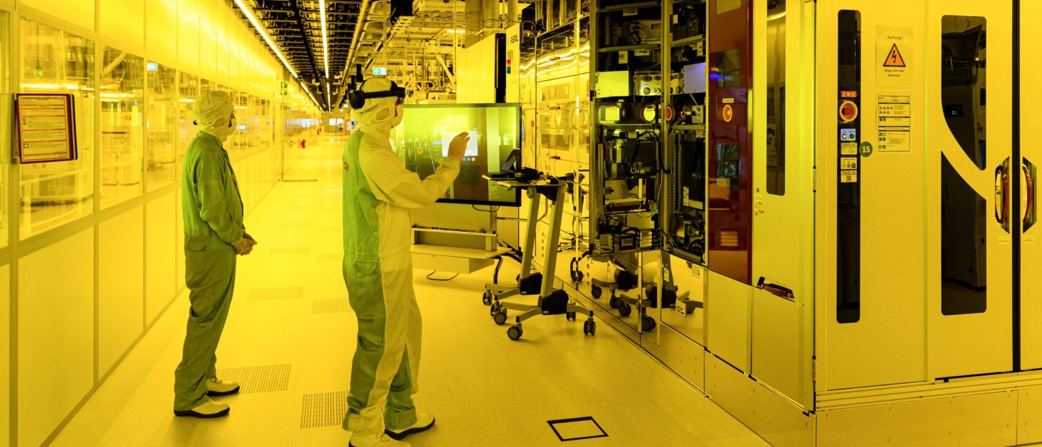  Two workers in protective gear and goggles work in a semiconductor manufacturing plant.