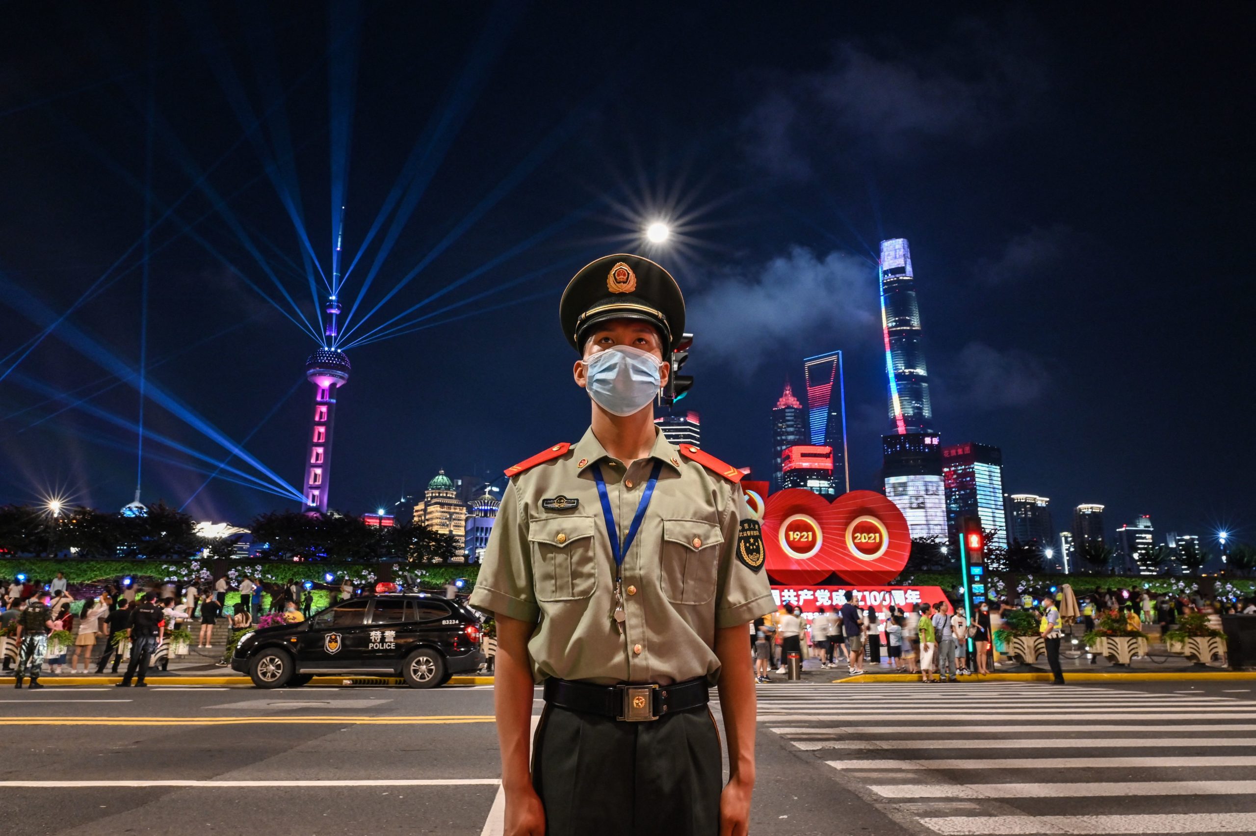 A Chinese paramilitary police stands guard while a light show is seen from the Bund in Shanghai on June 30, 2021, on the eve of the 100th anniversary of the Chinese Communist Party. (Photo by HECTOR RETAMAL/AFP via Getty Images)