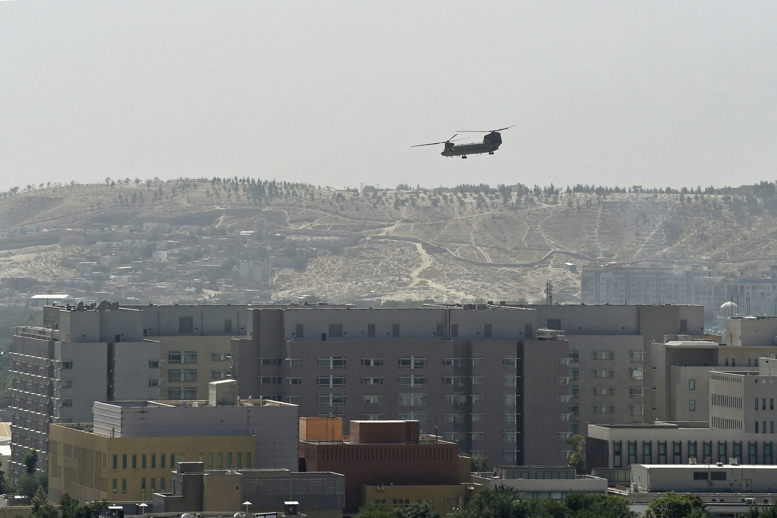 A U.S. Chinook military helicopter flies above the US embassy in Kabul on August 15, 2021. (Photo by WAKIL KOHSAR/AFP via Getty Images)