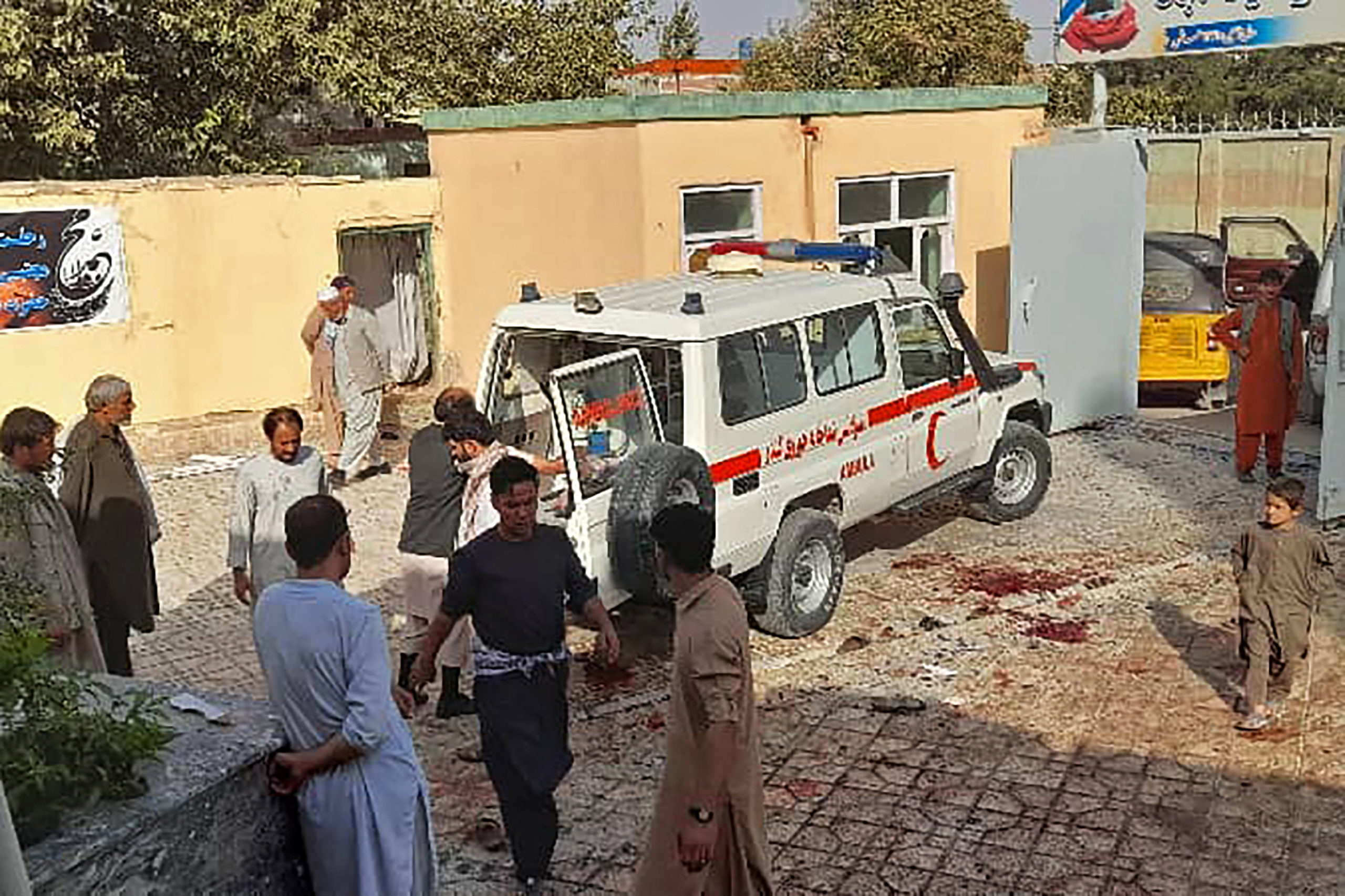 Afghan men stand next to an ambulance after a bomb attack at a mosque in Kunduz on October 8, 2021. (Photo by - / AFP) (Photo by -/AFP via Getty Images)