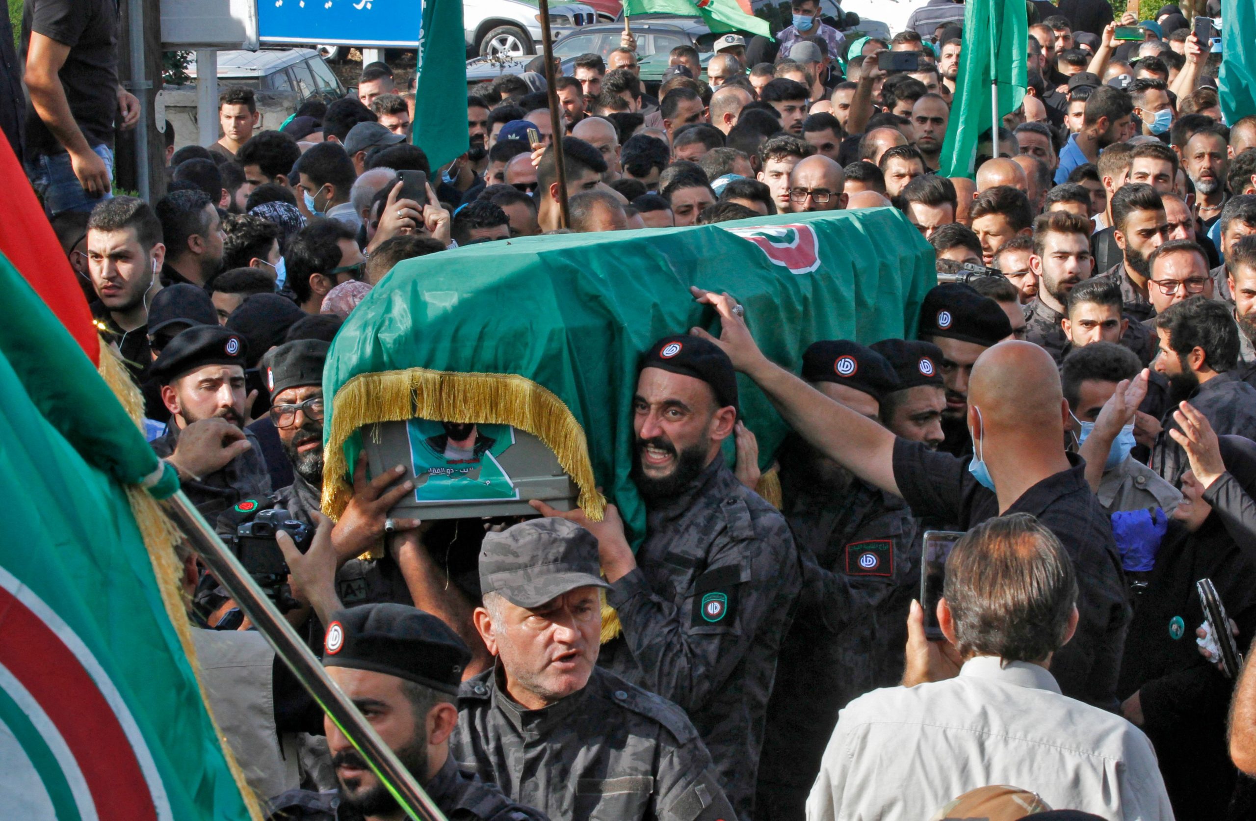 Members of the Shiite Amal movement carry the flag-draped casket of a fellow fighter who was killed in clashes in the Tayouneh neighbourhood of the capital Beirut's southern suburbs a day earlier, during his funeral in the southern Lebanese town of Al-Numairiyah, on October 15, 2021. (Photo by MAHMOUD ZAYYAT/AFP via Getty Images)