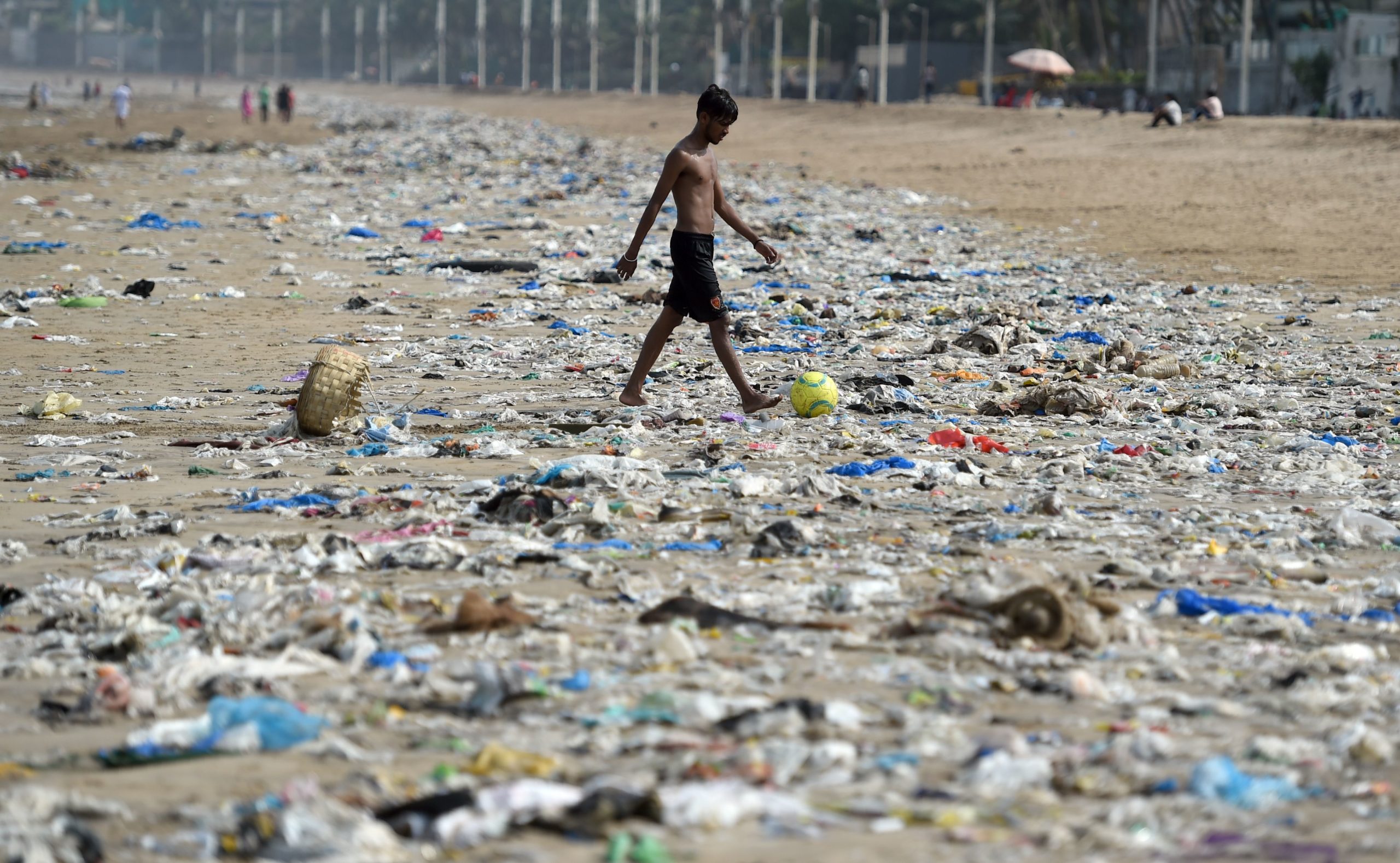 An Indian boy walks through plastic waste on Juhu beach in Mumbai on June 2, 2018. (Punit Paranjpe/AFP via Getty Images)