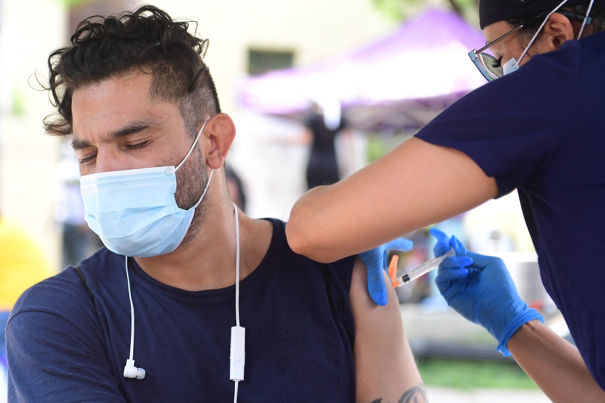 Juan Rodriguez (L) reacts while receiving Johnson & Johnson's Janssen Covid-19 vaccine administered by vocational nurse Christina Garibay at a Skid Row community outreach event where Covid-19 vaccines and testing were offered in Los Angeles, California on August 22, 2021. (Photo by Frederic J. BROWN / AFP) (Photo by FREDERIC J. BROWN/AFP via Getty Images)