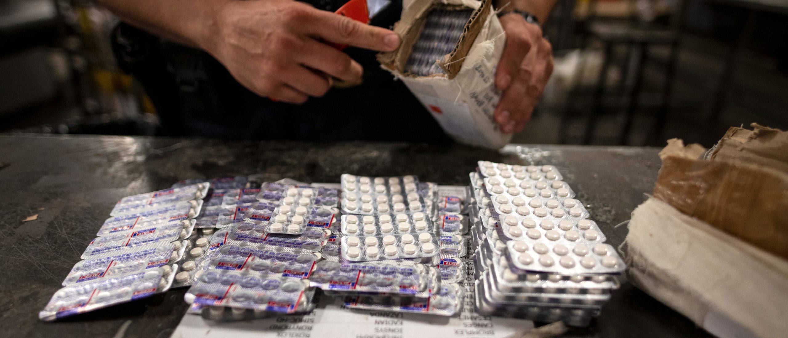 An officer from the US Customs and Border Protection, Trade and Cargo Division finds Oxycodon pills in a parcel at John F. Kennedy Airport's US Postal Service facility on June 24, 2019 in New York. (Photo by JOHANNES EISELE/AFP via Getty Images)
